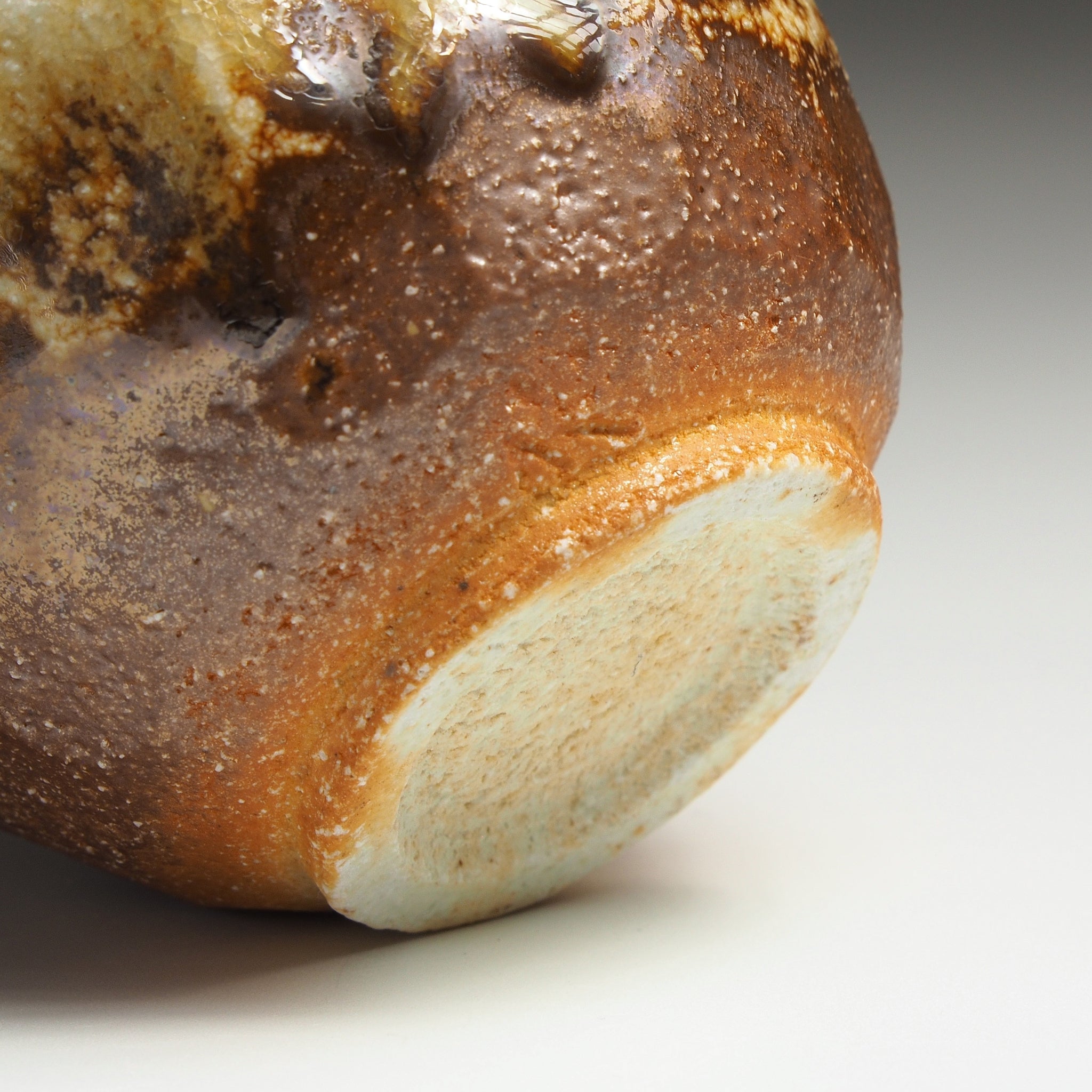 Close-up of a Ryoen handmade Shigaraki yunomi showing its warm brown fired surface, textured glaze, and pale unglazed foot.