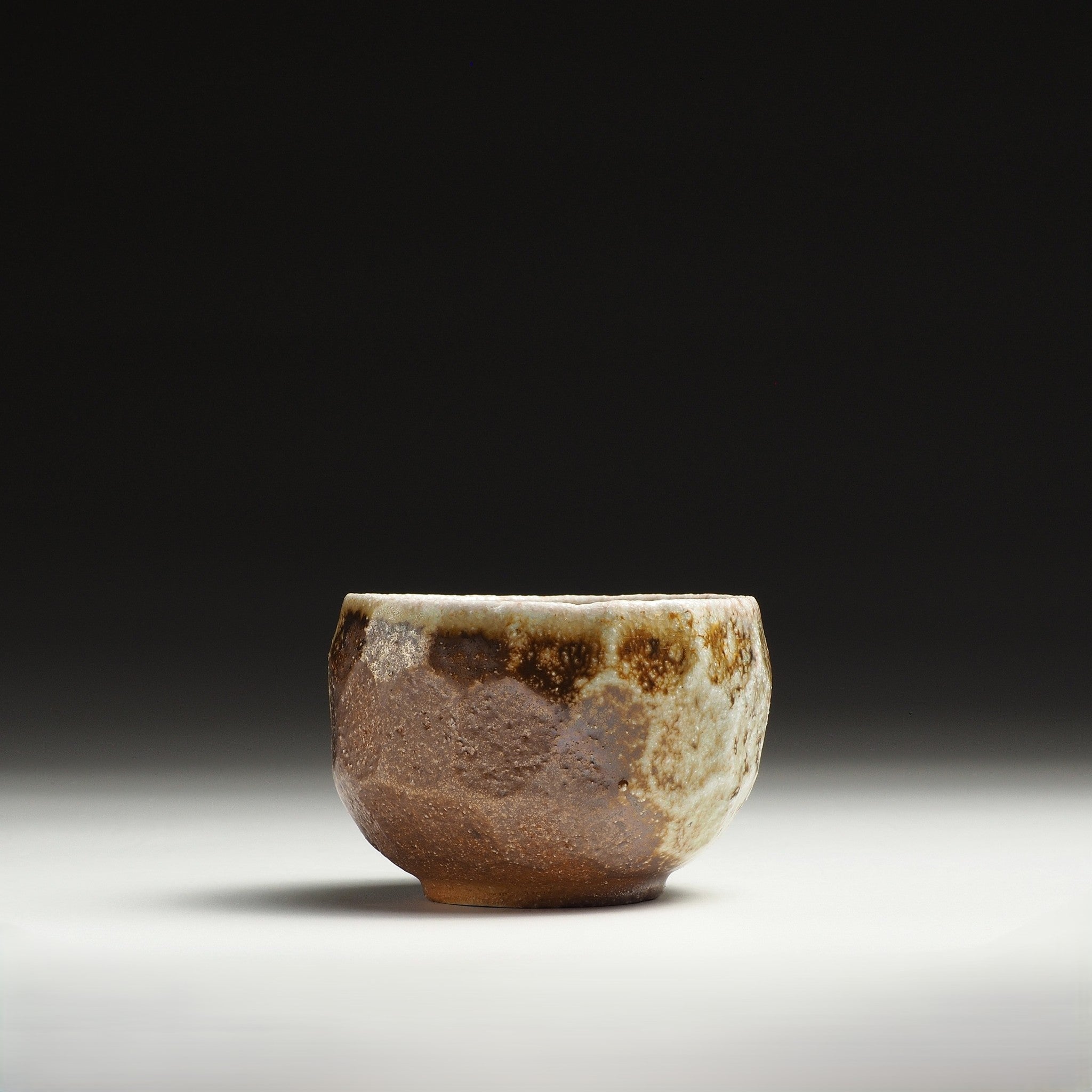 Ryoen handmade Shigaraki yunomi showing a brown clay body with naturally irregular beige and gray glaze.
