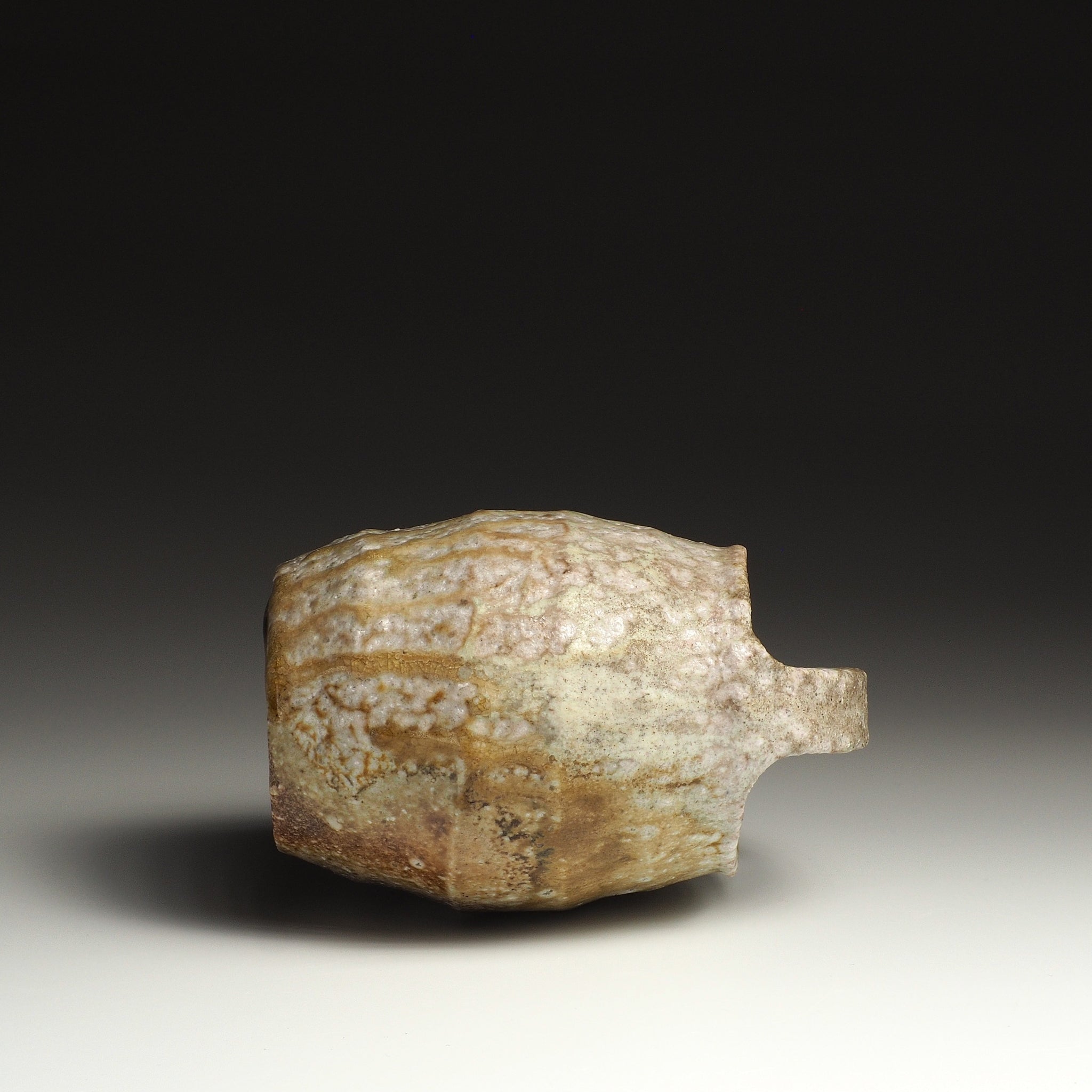 Side view of the Setsugan handmade Shigaraki flower vase resting horizontally, showing its rounded body and handle profile.