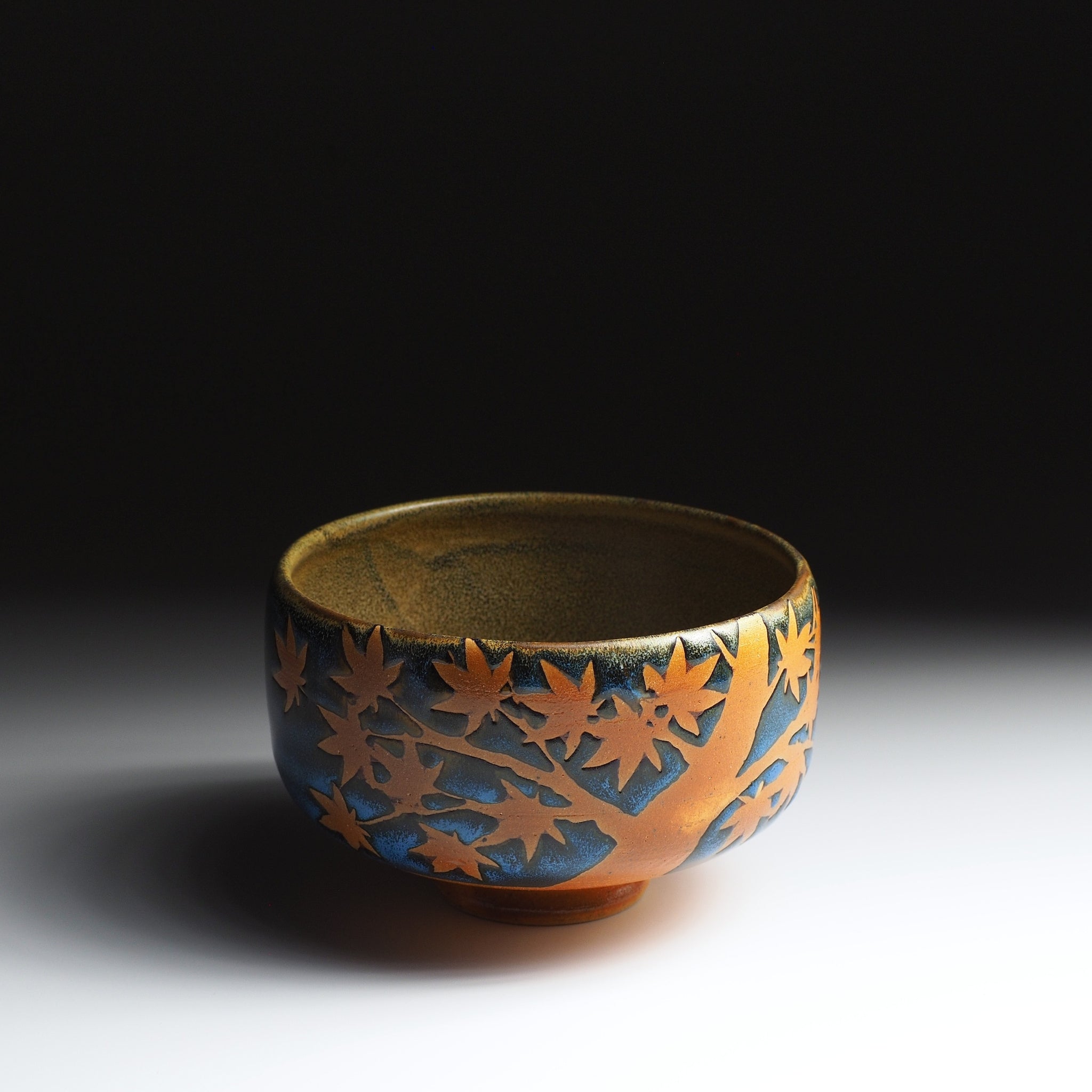 Sōshū matcha bowl, front view, momiji tree motif in natural clay against deep blue Nanasai Tenmoku glaze
