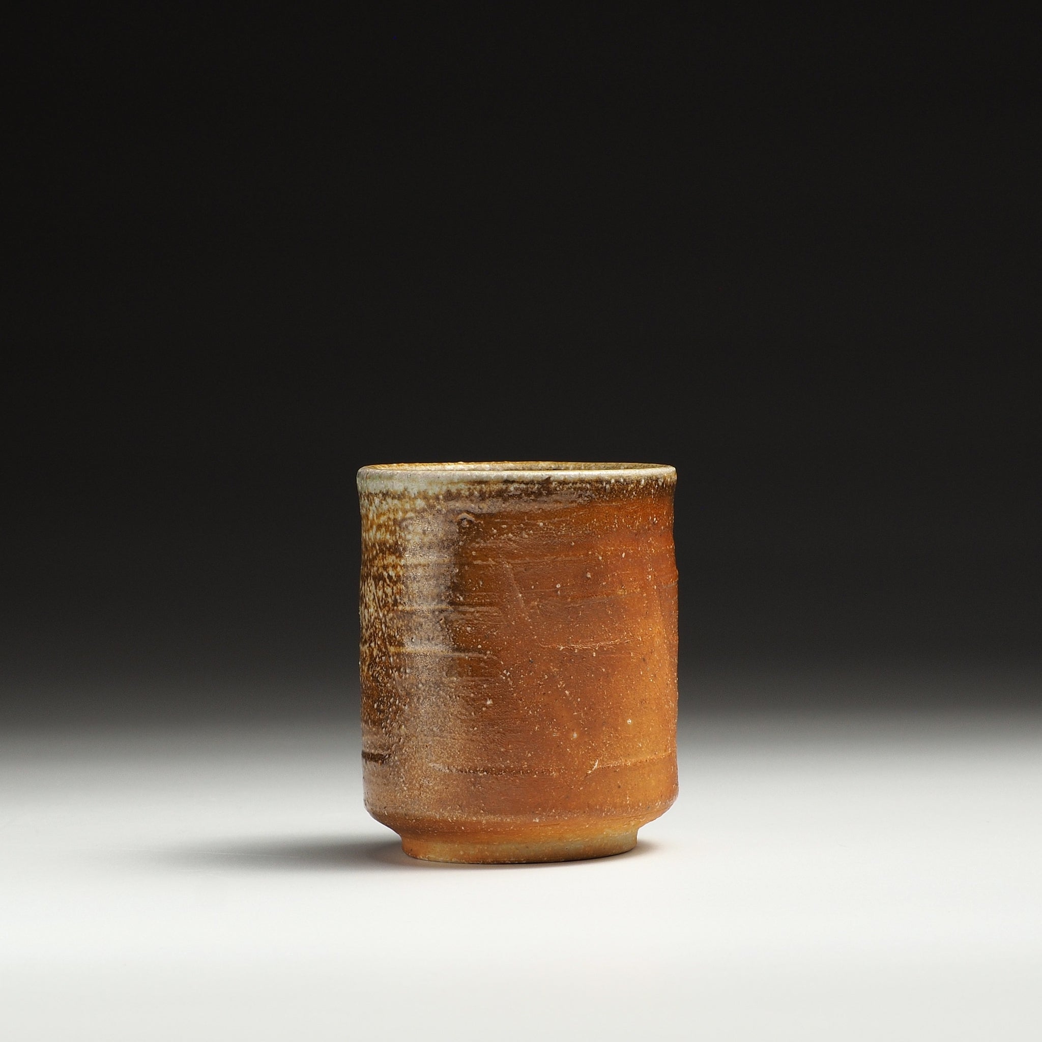 Single Yubae handmade Shigaraki yunomi with a softly rounded cylindrical form and orange-brown surface.