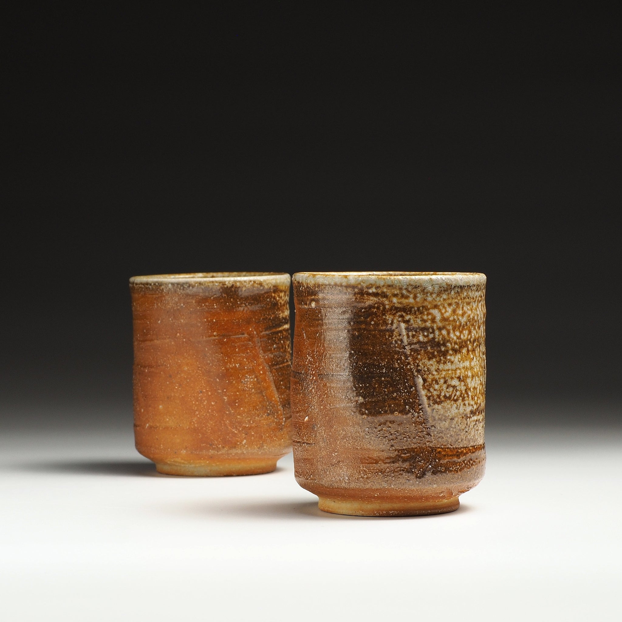 Two Yubae handmade Shigaraki yunomi teacups with warm brown, beige, and ash-fired surfaces.