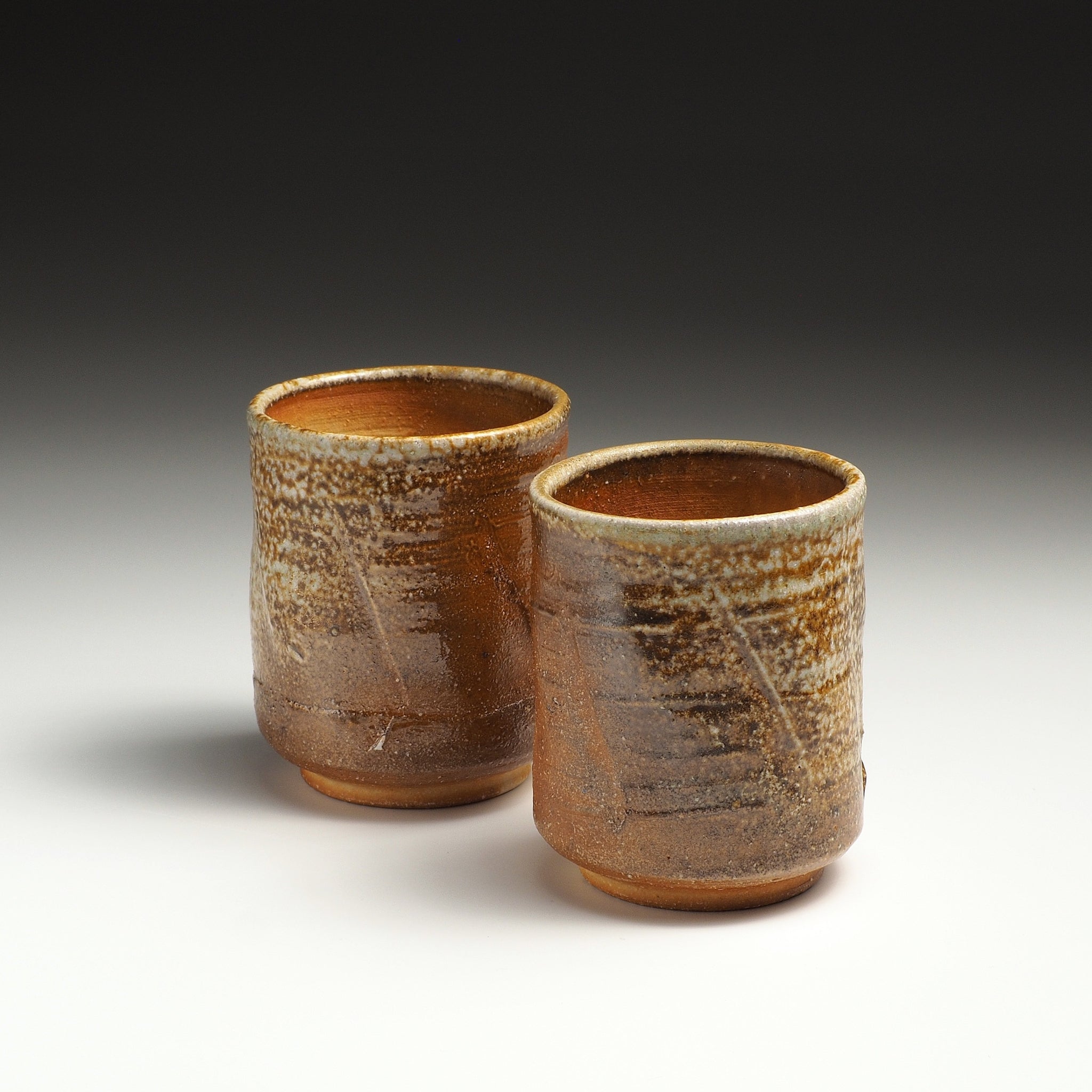 Two Yubae handmade Shigaraki yunomi teacups standing side by side with contrasting earthy firing tones.