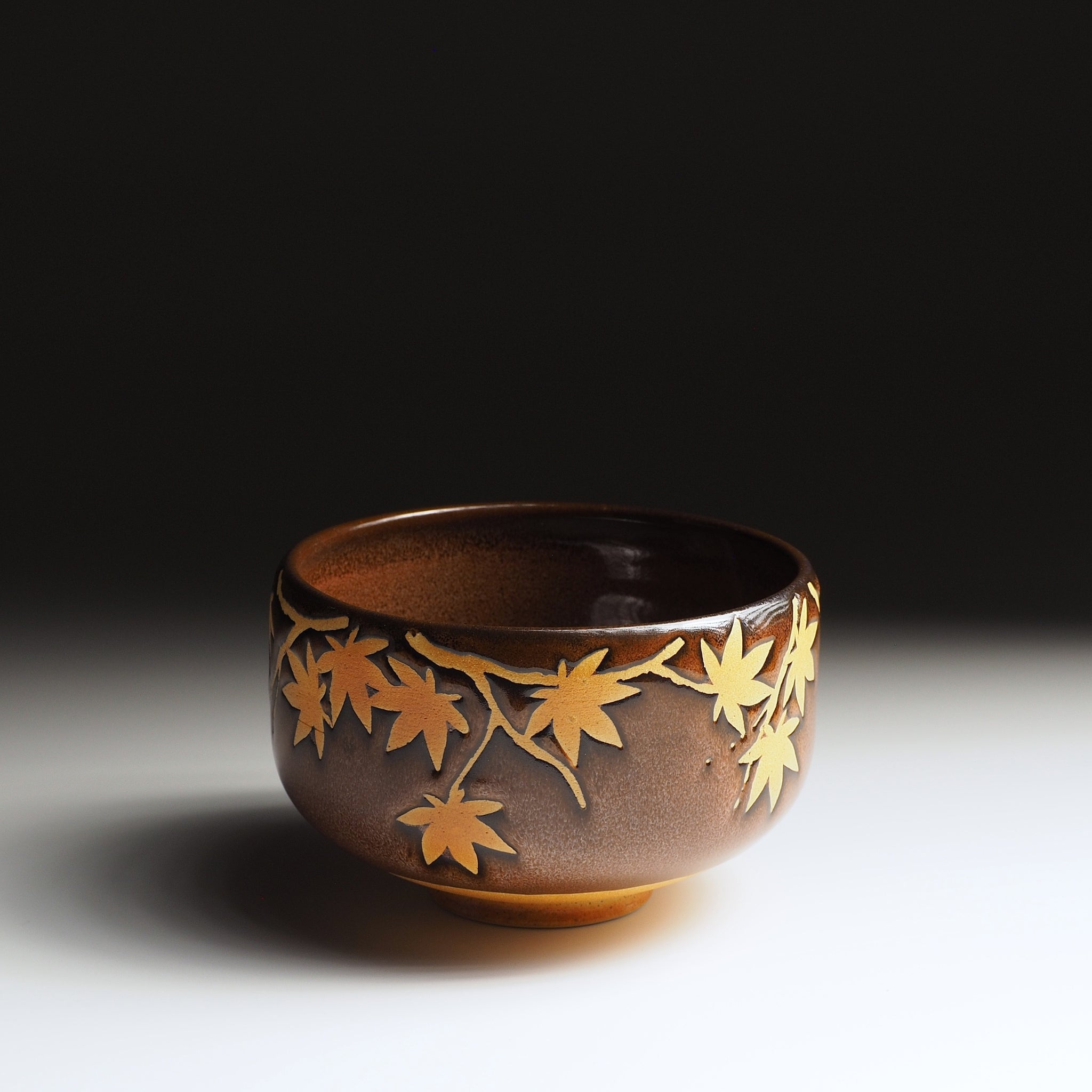 Yūkaede matcha bowl, full side view, cascading momiji branch in natural clay on Nanasai Tenmoku glaze, Nunobiki Kiln
