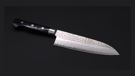 A santoku blade with tsuchime on a black background