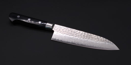 A santoku blade with tsuchime on a black background