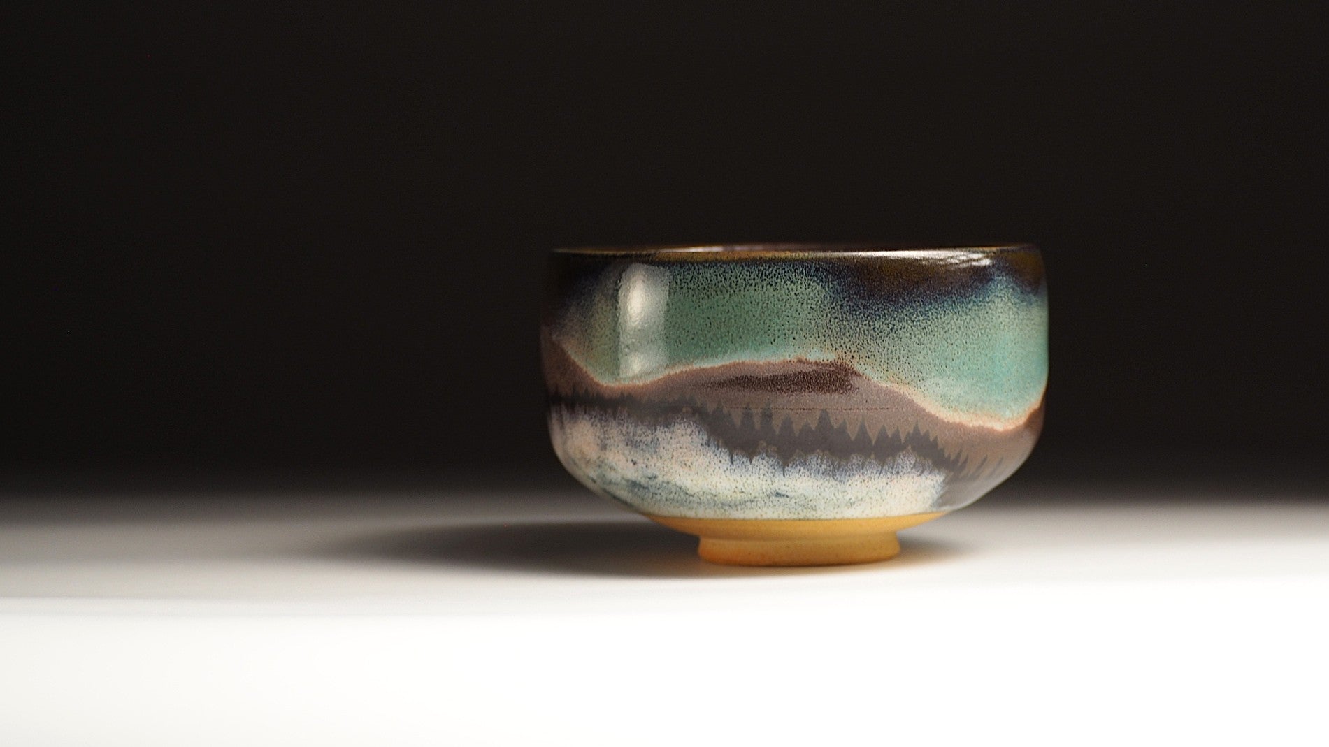 A handmade matcha bowl featuring an aurora inspierd decoration on a fading background | Tsukushi