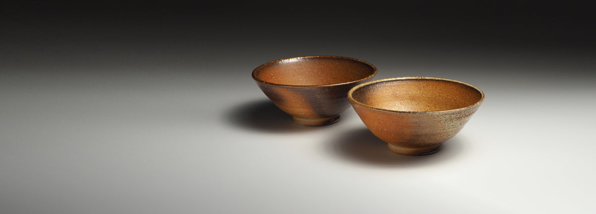 Handmade Shigaraki bowls on a faded background.