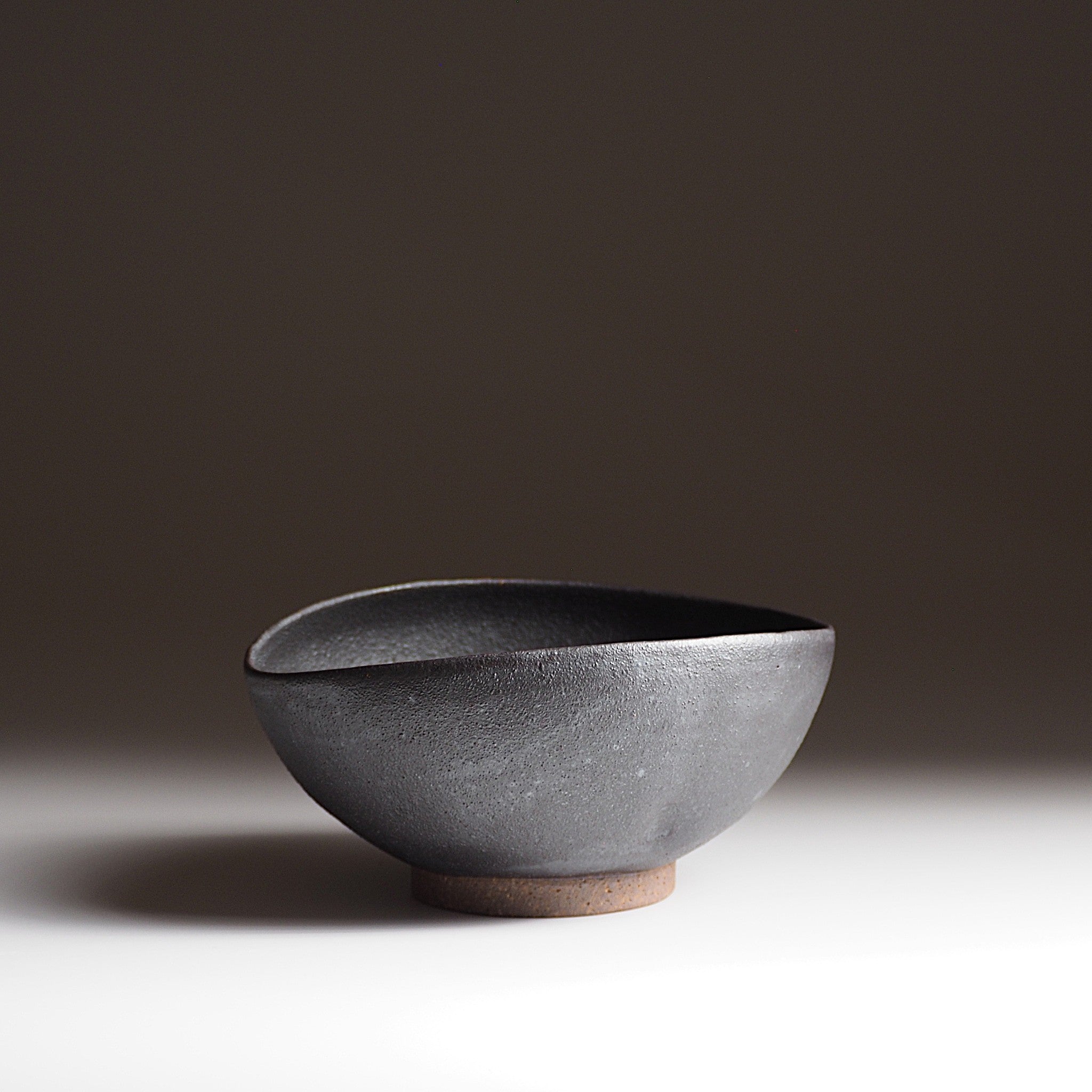 Handcrafted black Japanese ceramic bowl on a gradient background, Tsukushi
