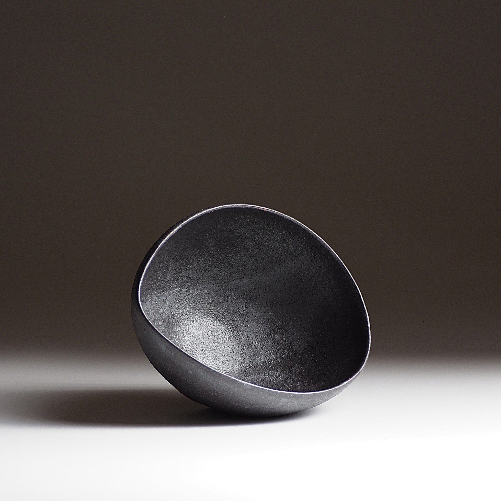 Handcrafted  black Japanese ceramic bowl on a dark gradation background, Tsukushi