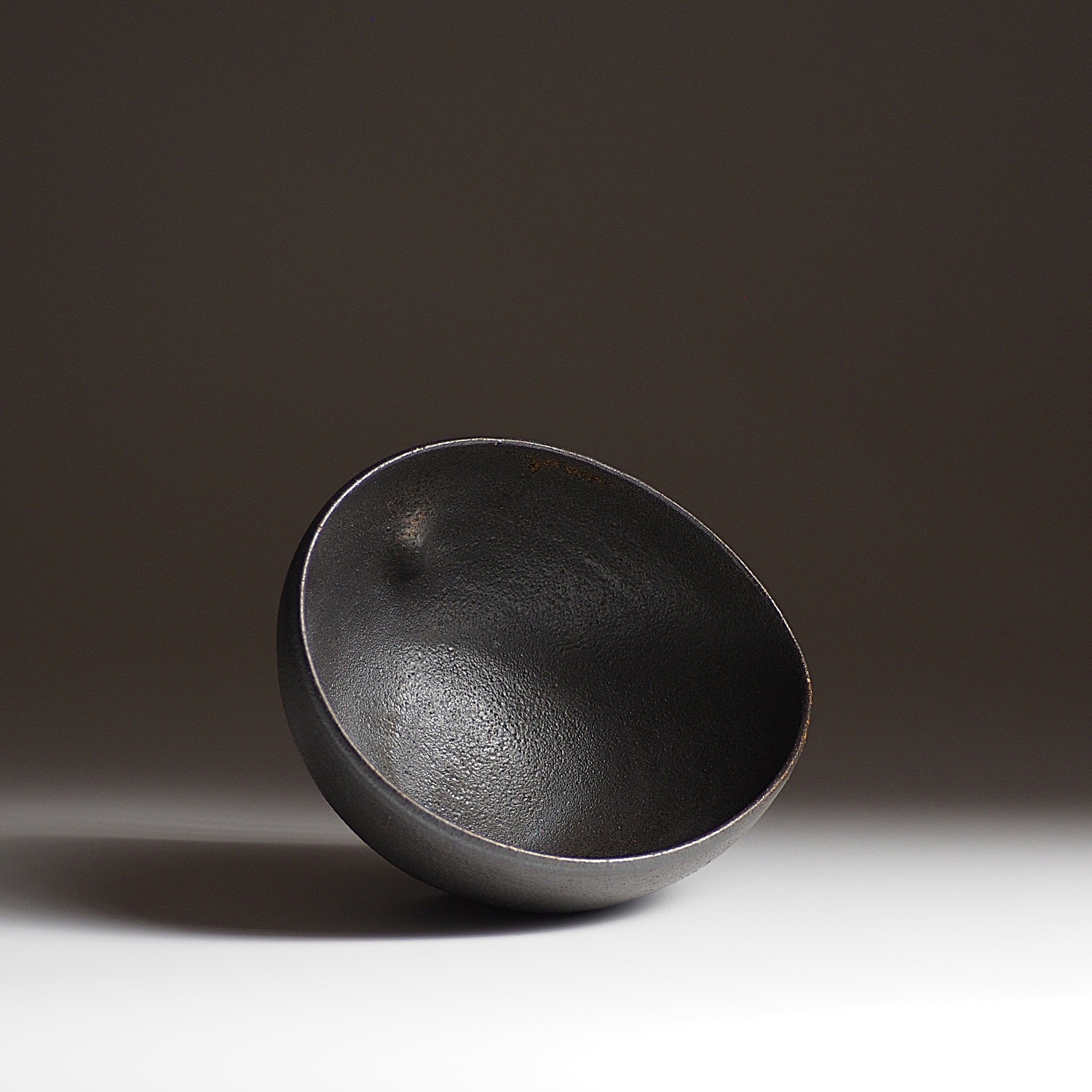Top view of handcrafted black Japanese  ceramic bowl on a dark gradation background, Tsukushi