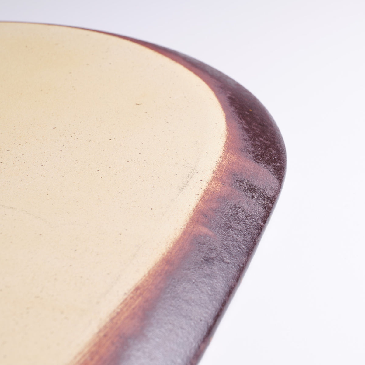 Close-up of the Hanami Green Cherry Blossoms Plate underside, revealing the curved brown ceramic edge and smooth cream-colored base.