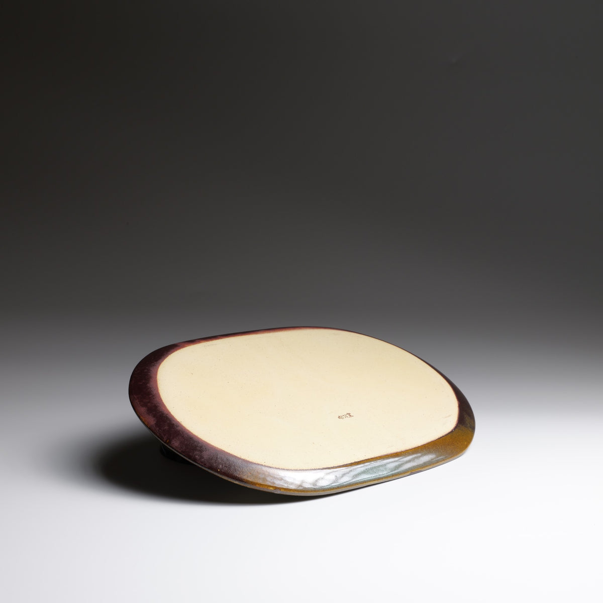 Underside of the Hanami Green Cherry Blossoms Plate, featuring a smooth cream-colored ceramic base and dark brown edges.