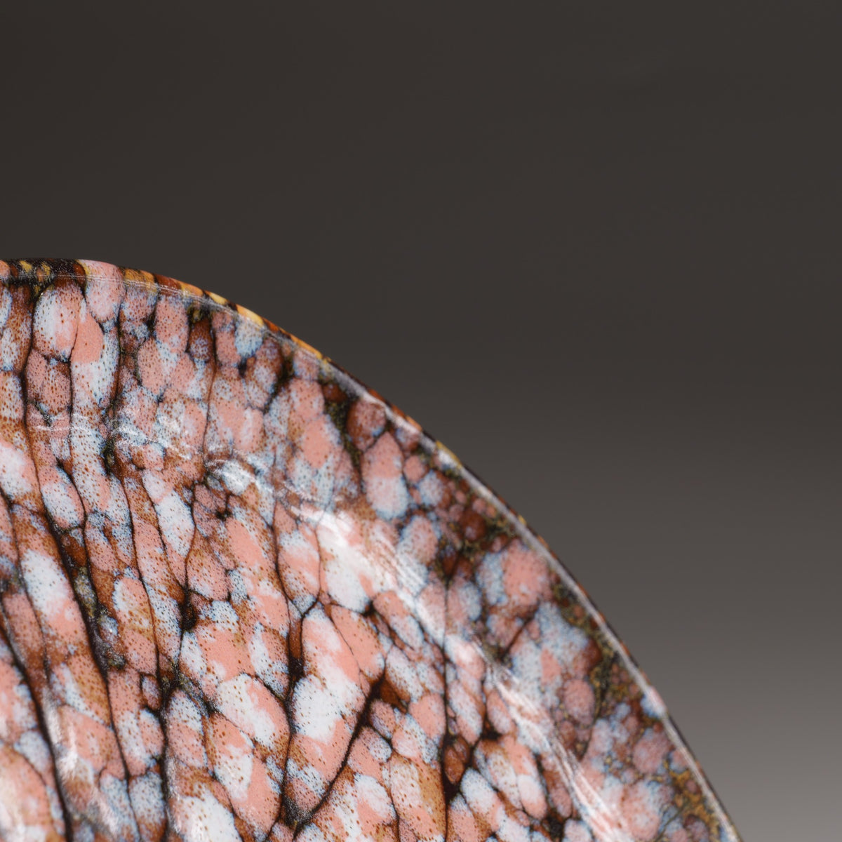 Close-up of the Hanami ceramic plate revealing delicate pink cherry blossoms, dark branching lines, and intricate glaze textures.