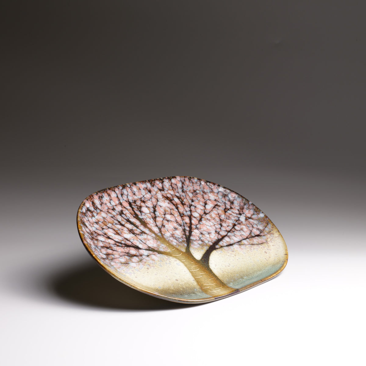 Angled view of the Hanami Green Cherry Blossoms Plate, showing its gently curved shape and hand-painted cherry blossom tree design.