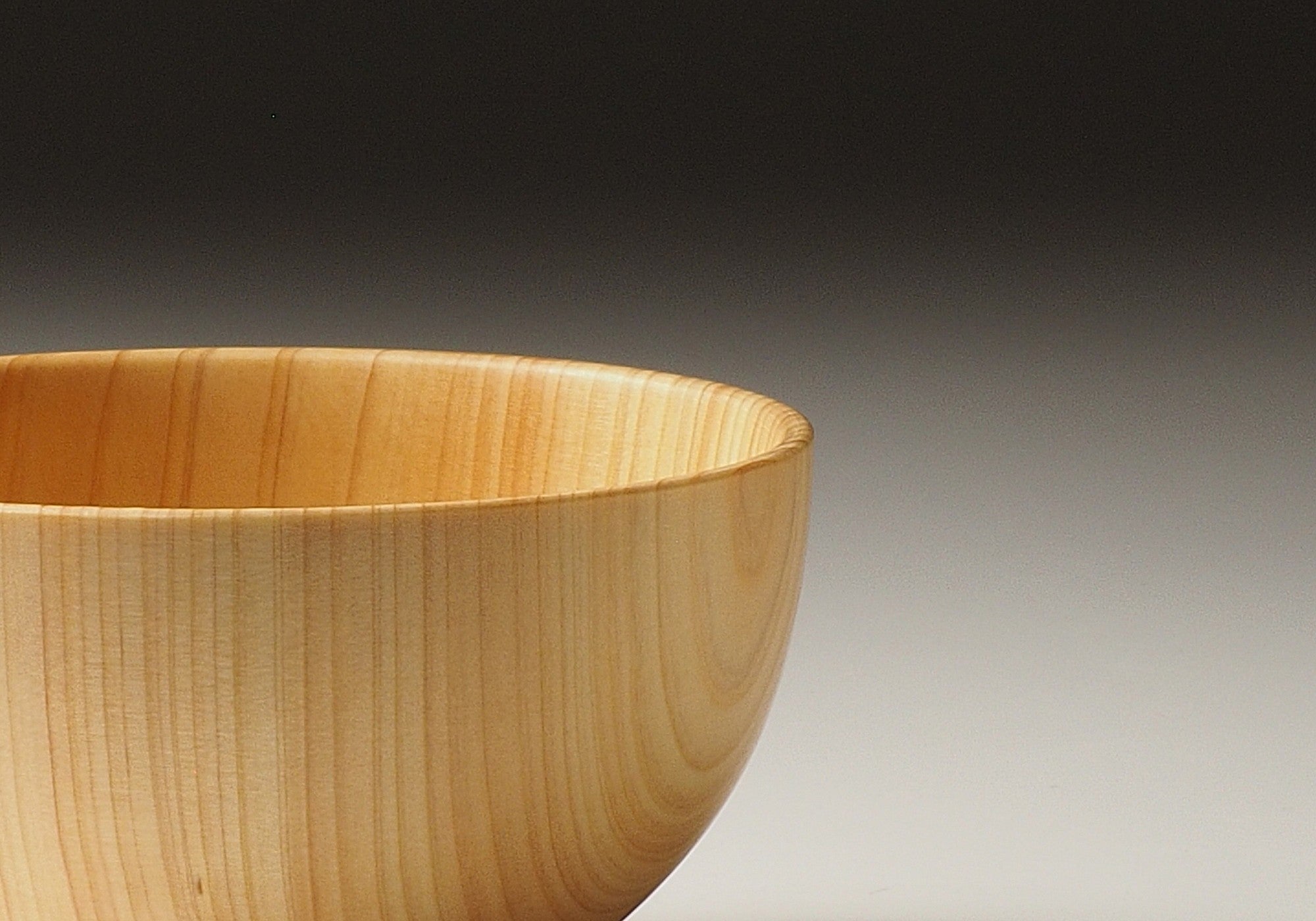 A detail of a Japanese wooden macha tea bowl on a beige background. Tsukushi 