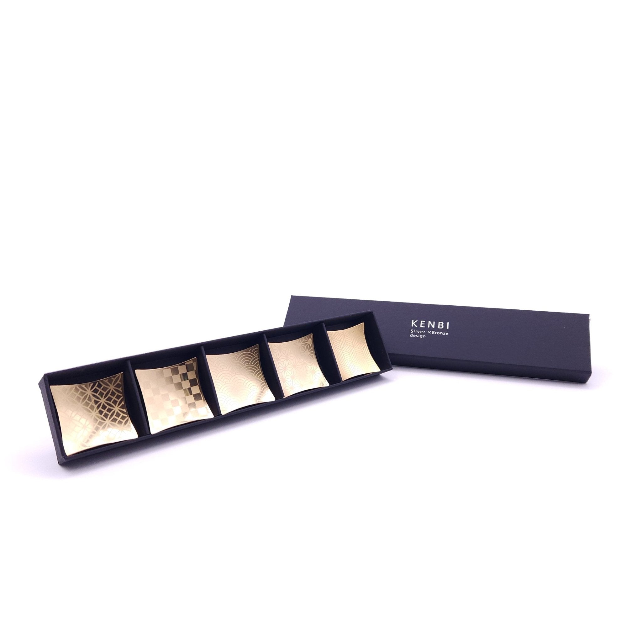 A set of five Japanese Chopsticks rest in golden metal inside a box.