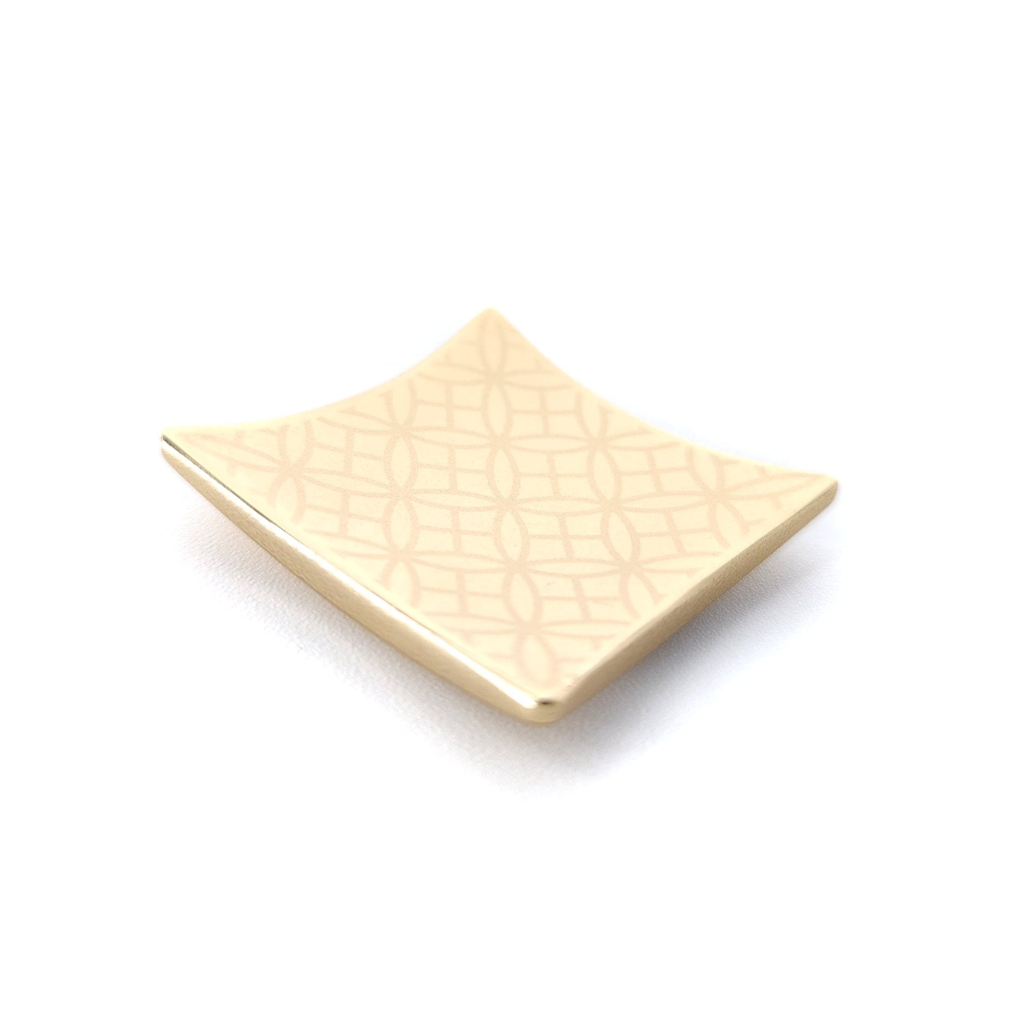 A Japanese Chopsticks rest in golden metal with squares and rounds pattern. Top side view. 