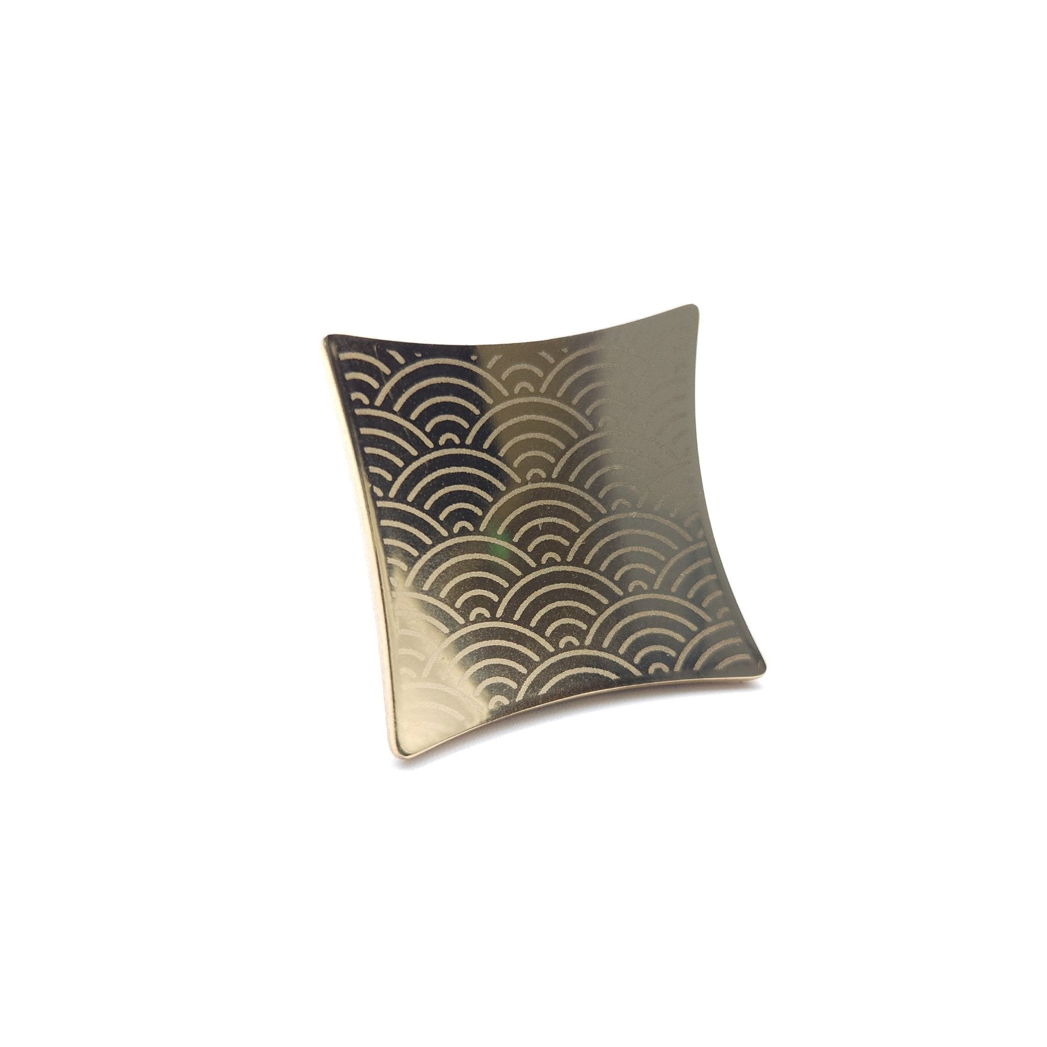 A Japanese Chopsticks rest in golden metal with waves pattern. Front view. 