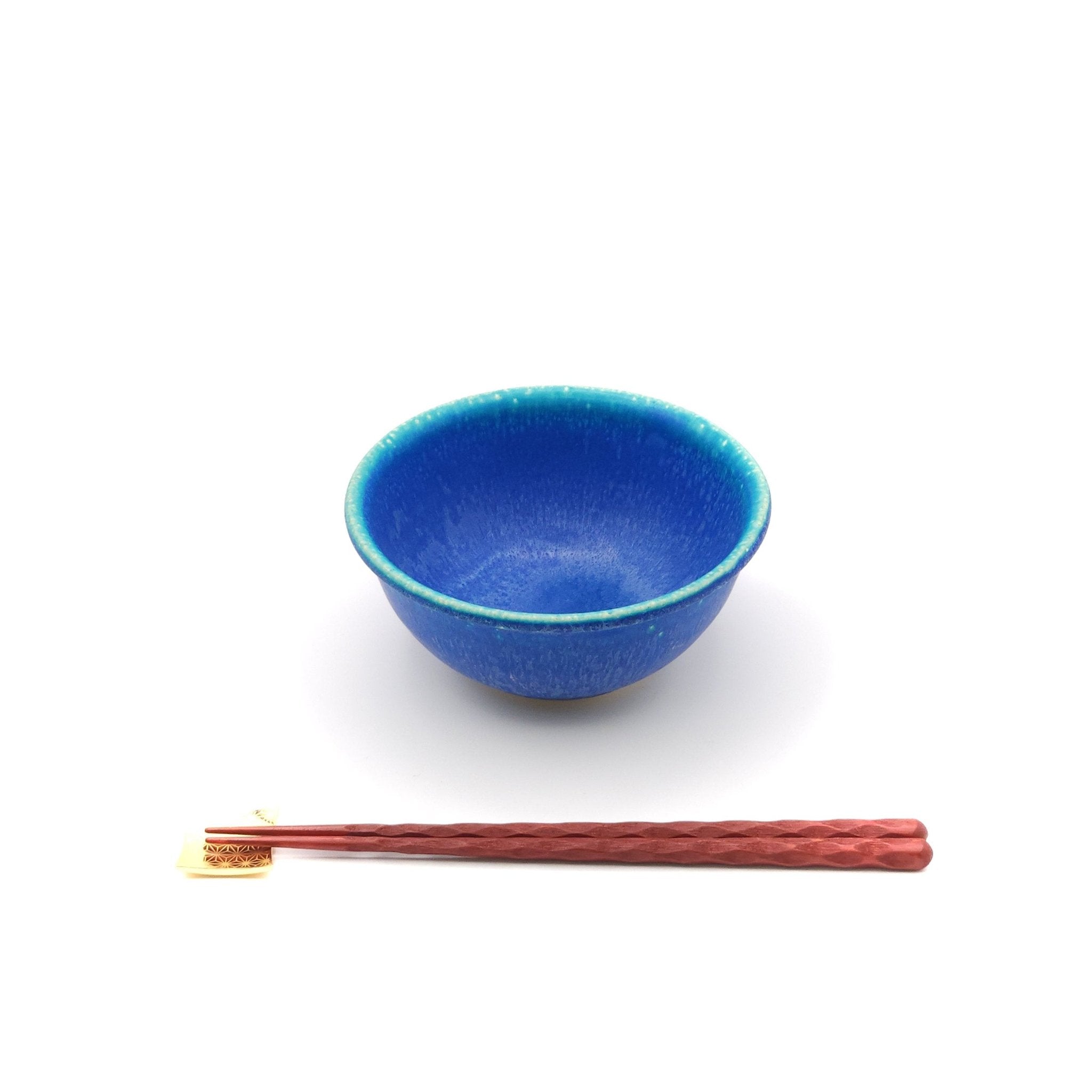 ront view of a Japanese pottery bowl, turquoise color with chopsticks.