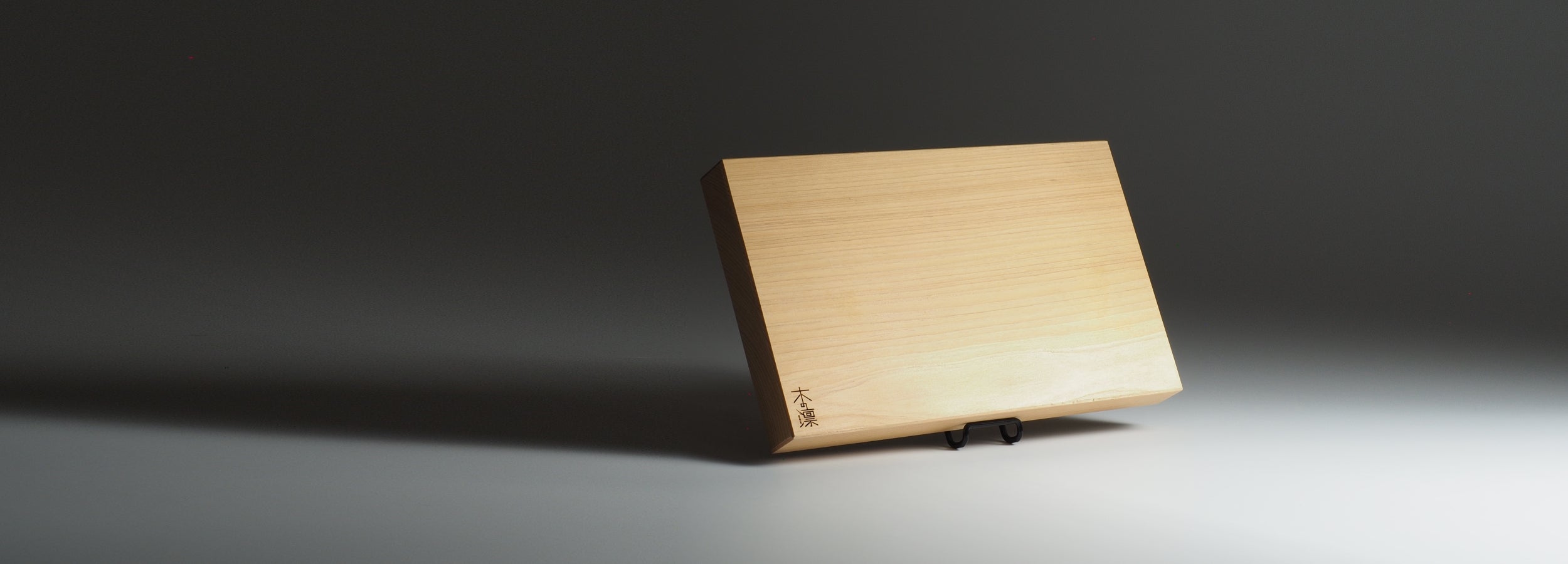 Wooden japanese cutting board on a dark gray background. Tsukushi