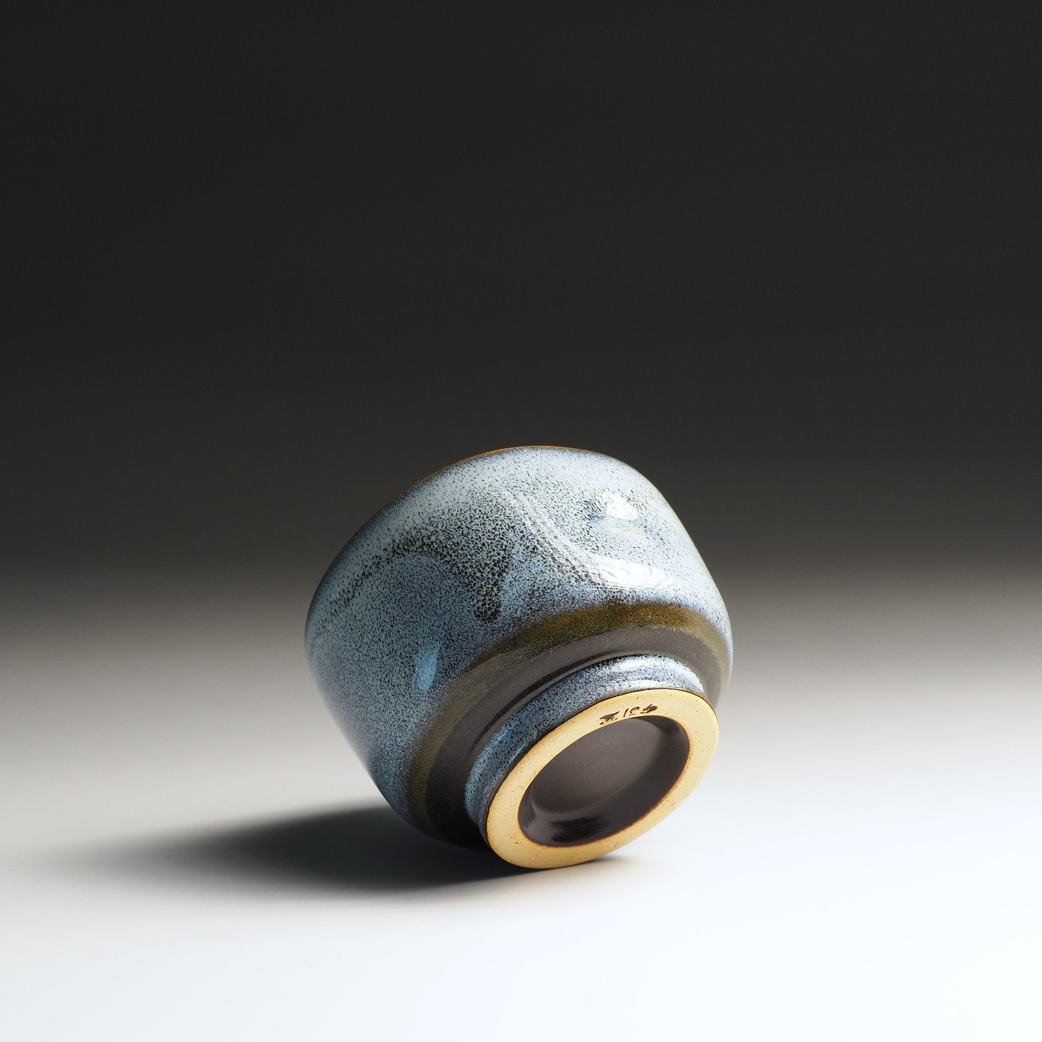 Japanese Ceramic tea cup with blue glaze and gold interior on a gradient background