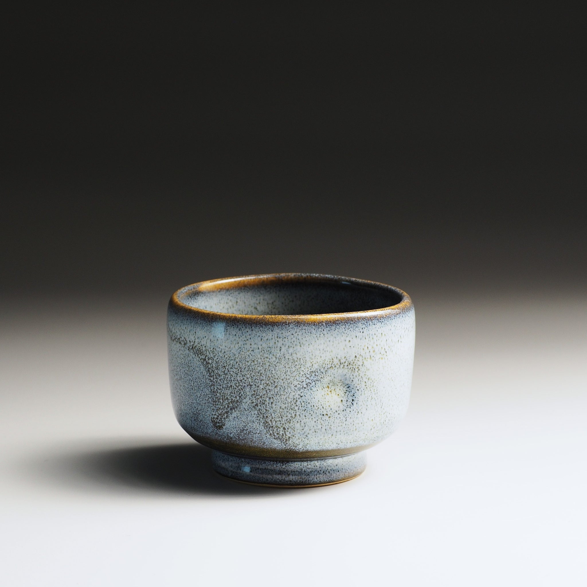 Front view of a Japanese yunomi with wabi sabi glaze on a gradient background