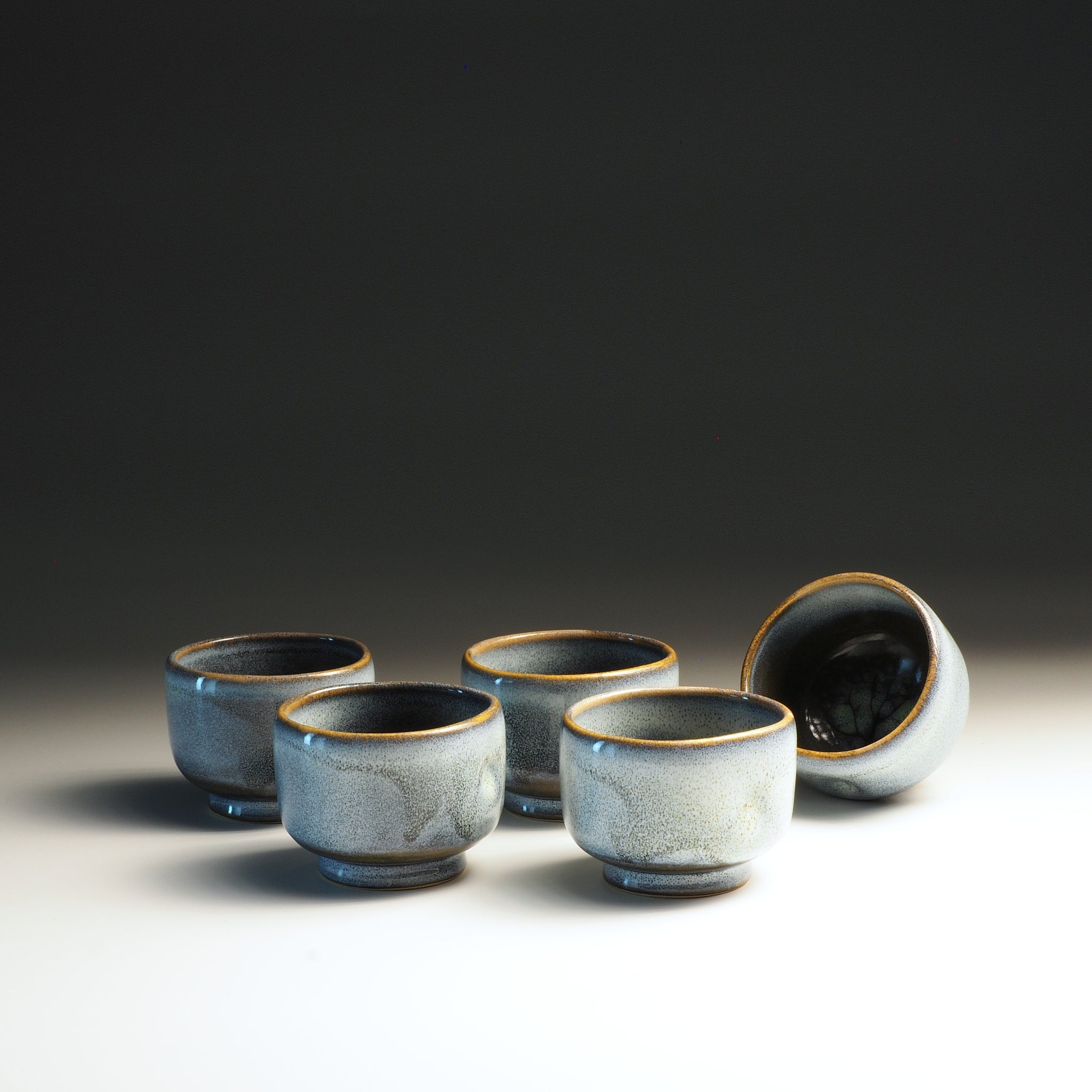 Set of five Japanese ceramic teacups with a dark background