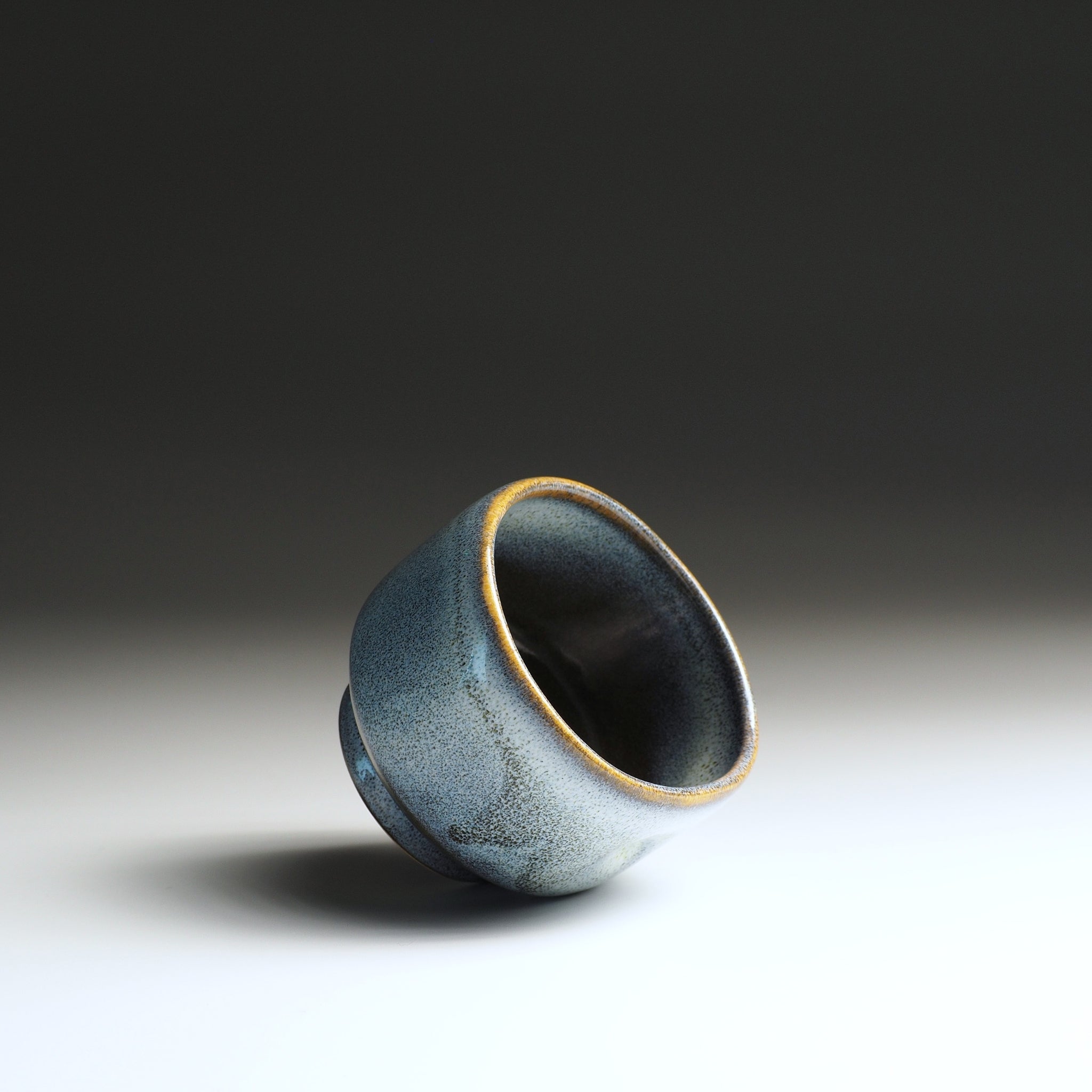 Side view of a ceramic yunomi teacup with wabi-sabi glaze on a gradient background
