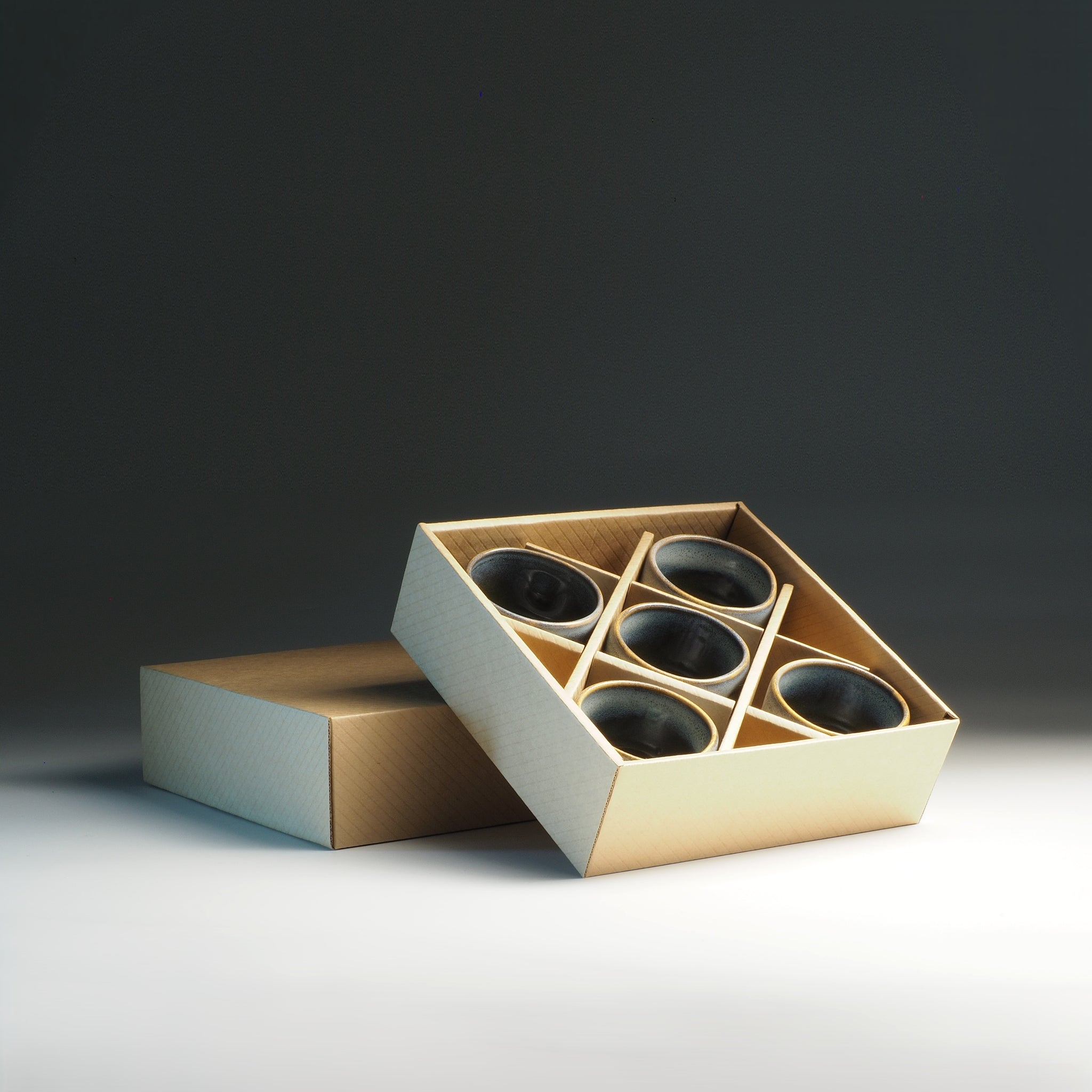 Gift carton box with inside five Japanese ceramic yunomi on a dark background