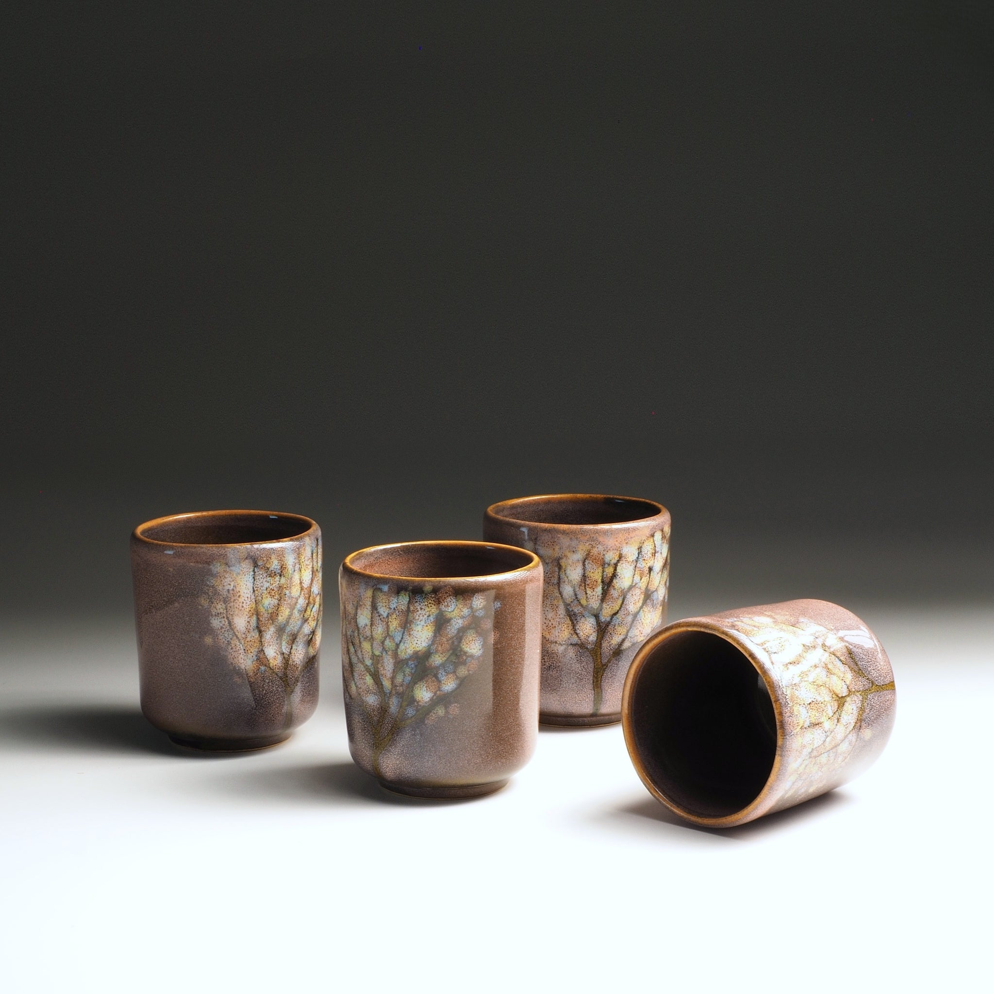 Set of four pink yunomi teacups with a textured surface on a gradient background