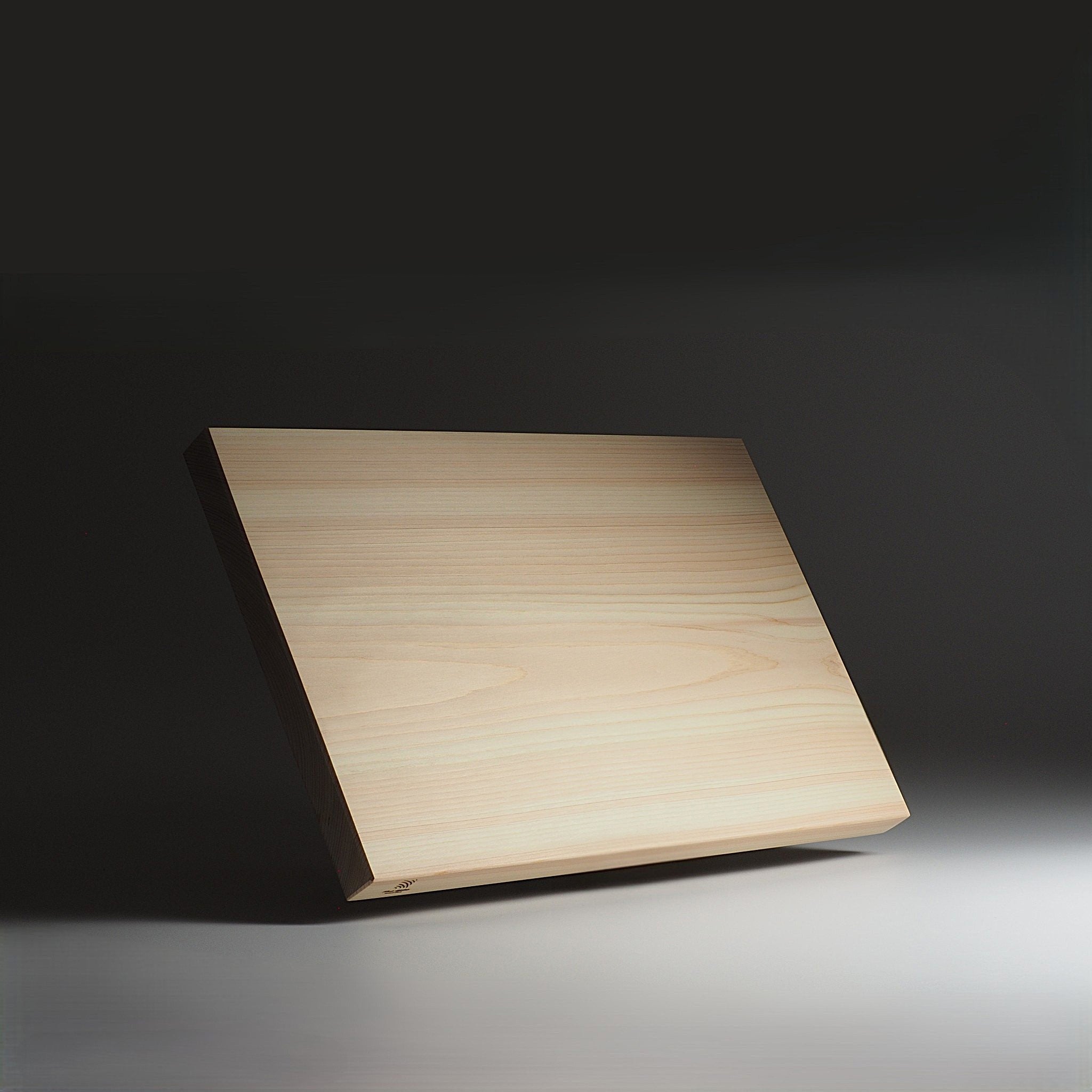 Japanese wooden cutting board showing the surface on a dark background. Tsukushi