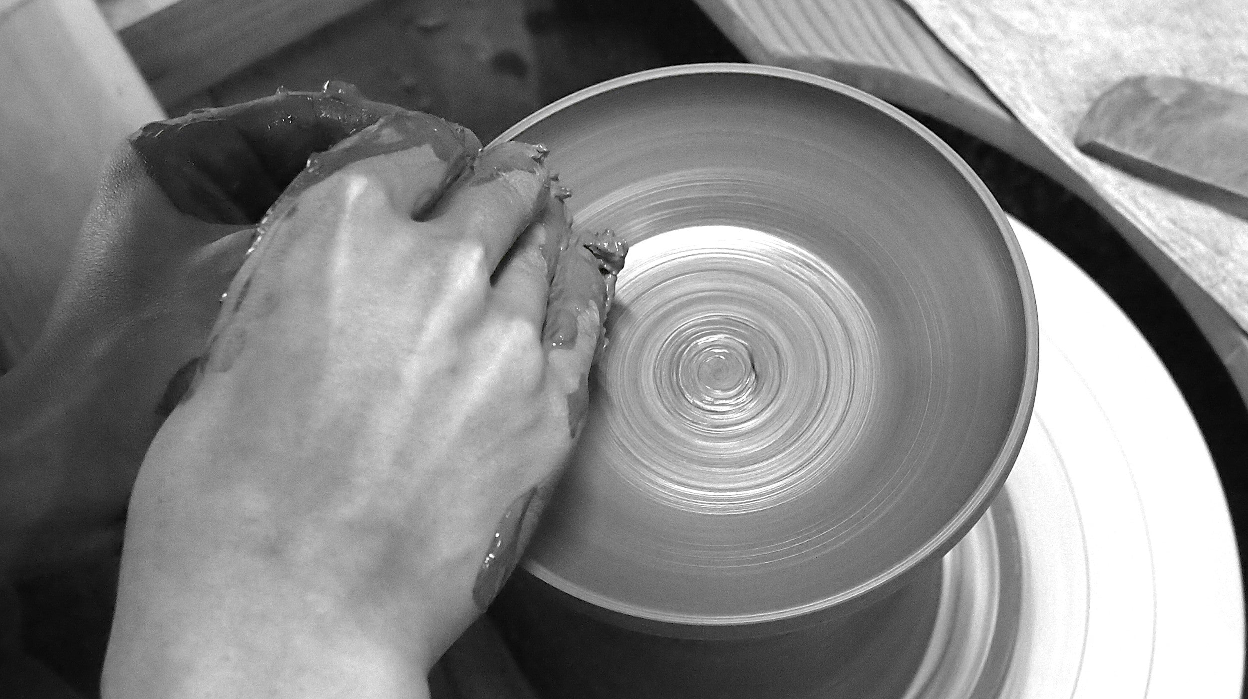 Person shaping a pot on a Japanese pottery wheel with a close-up view, Tsukushi