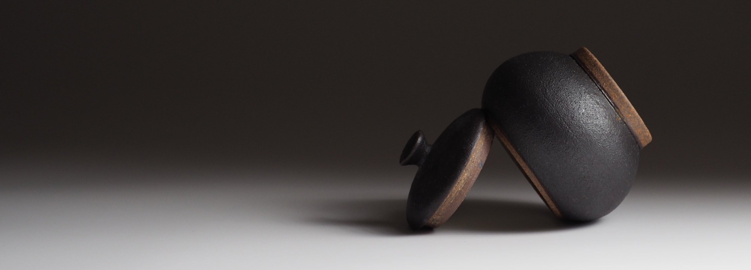 Japanese handcrafted black ceramic Chawanmushi bowl beige background, Tsukushi