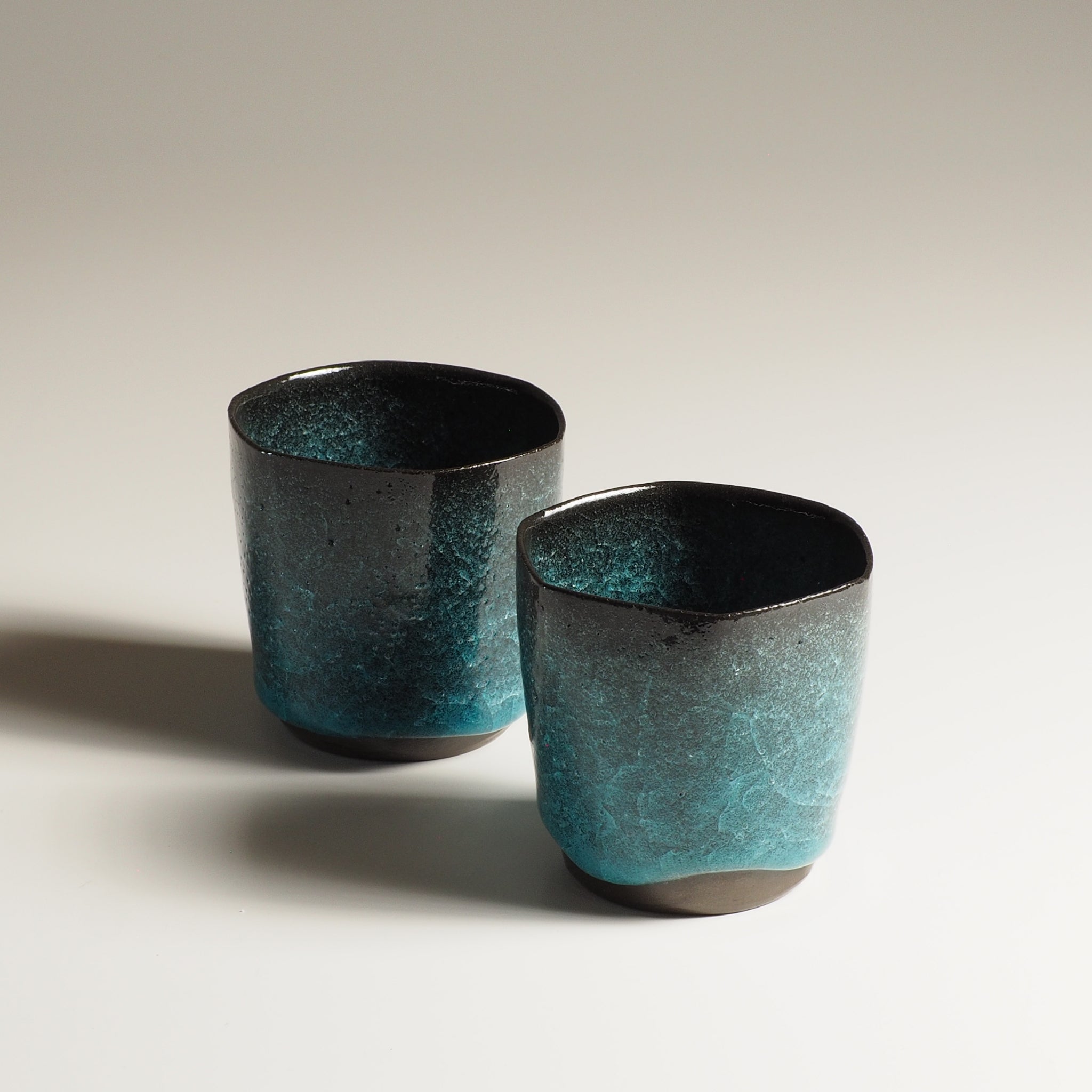 Two Japanese handcrafted crazing ceramic Teacups beige background shadow, Tsukushi