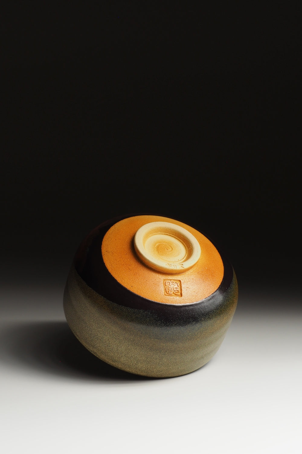 Bottom view of a pottery matcha bowl on a gradient background. Tsukushi