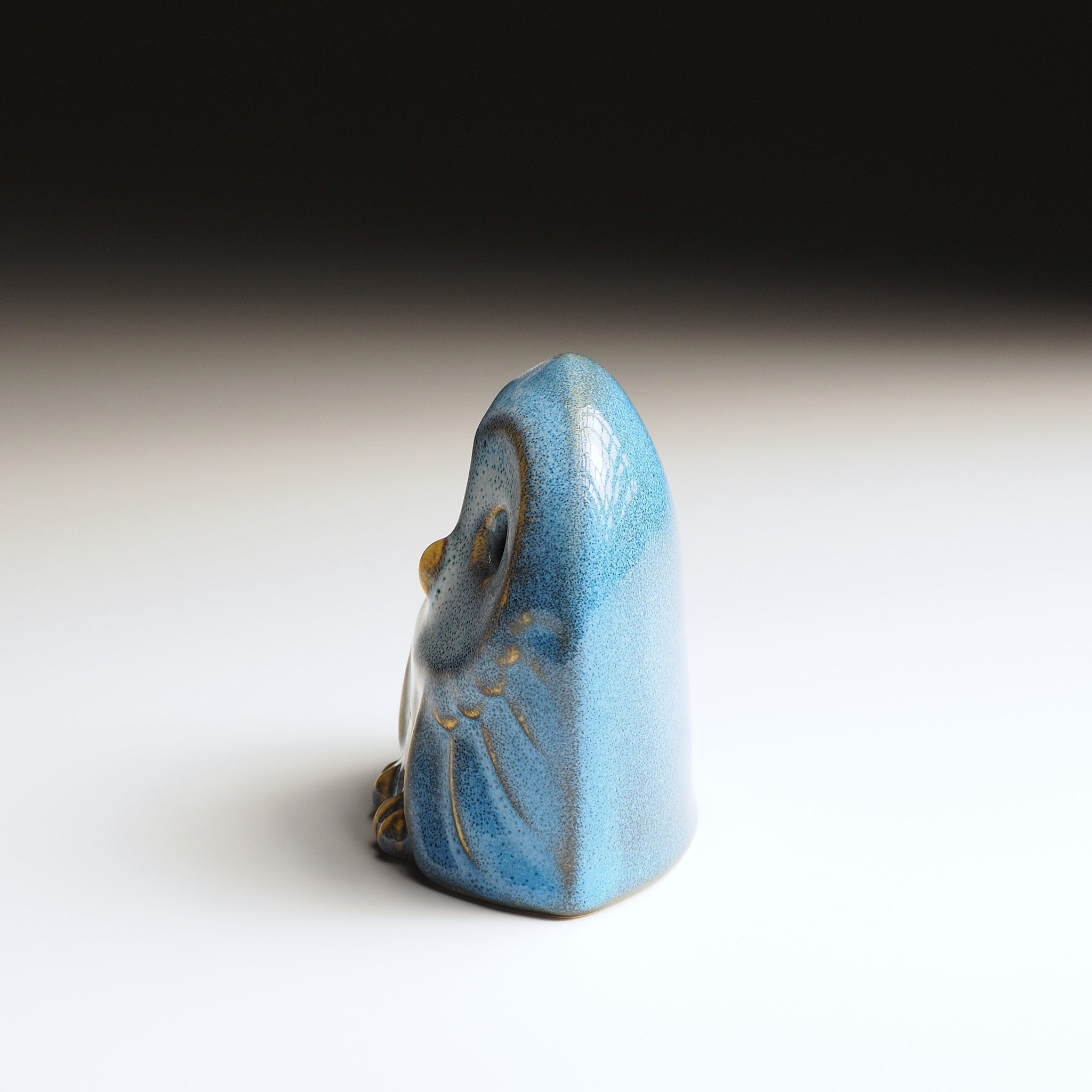 Left side view of Engifuku owl figurine by Kazuhiro Kojima, blue speckled ceramic glaze, golden wing details, gradient background.