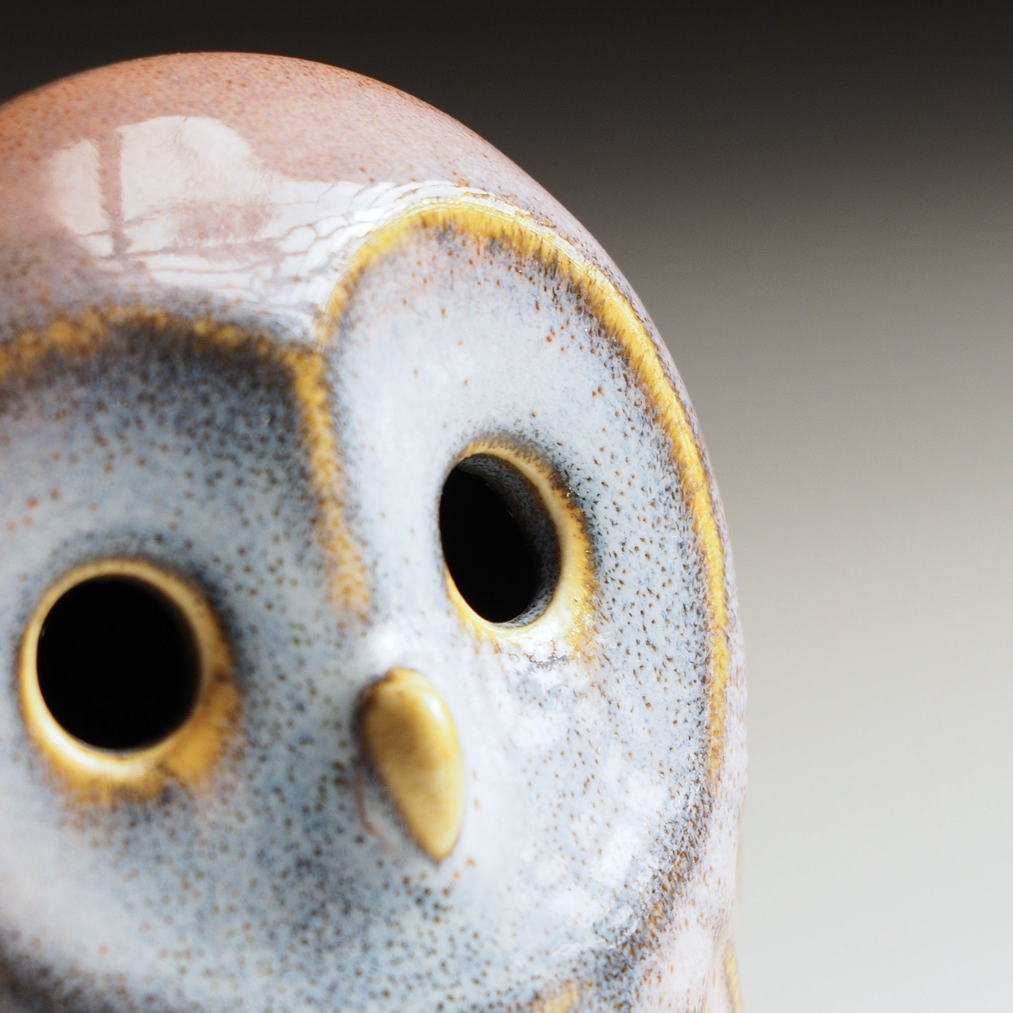 Close-up detail of Engifuku owl figurine by Kazuhiro Kojima, pink and grey speckled glaze, golden-rimmed hollow eyes and beak.