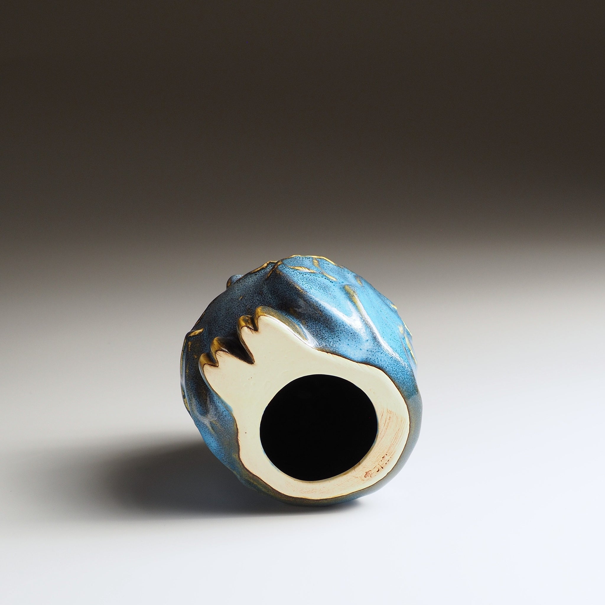 Bottom view of the small Fukumori ceramic owl ornament showing the circular opening in its base