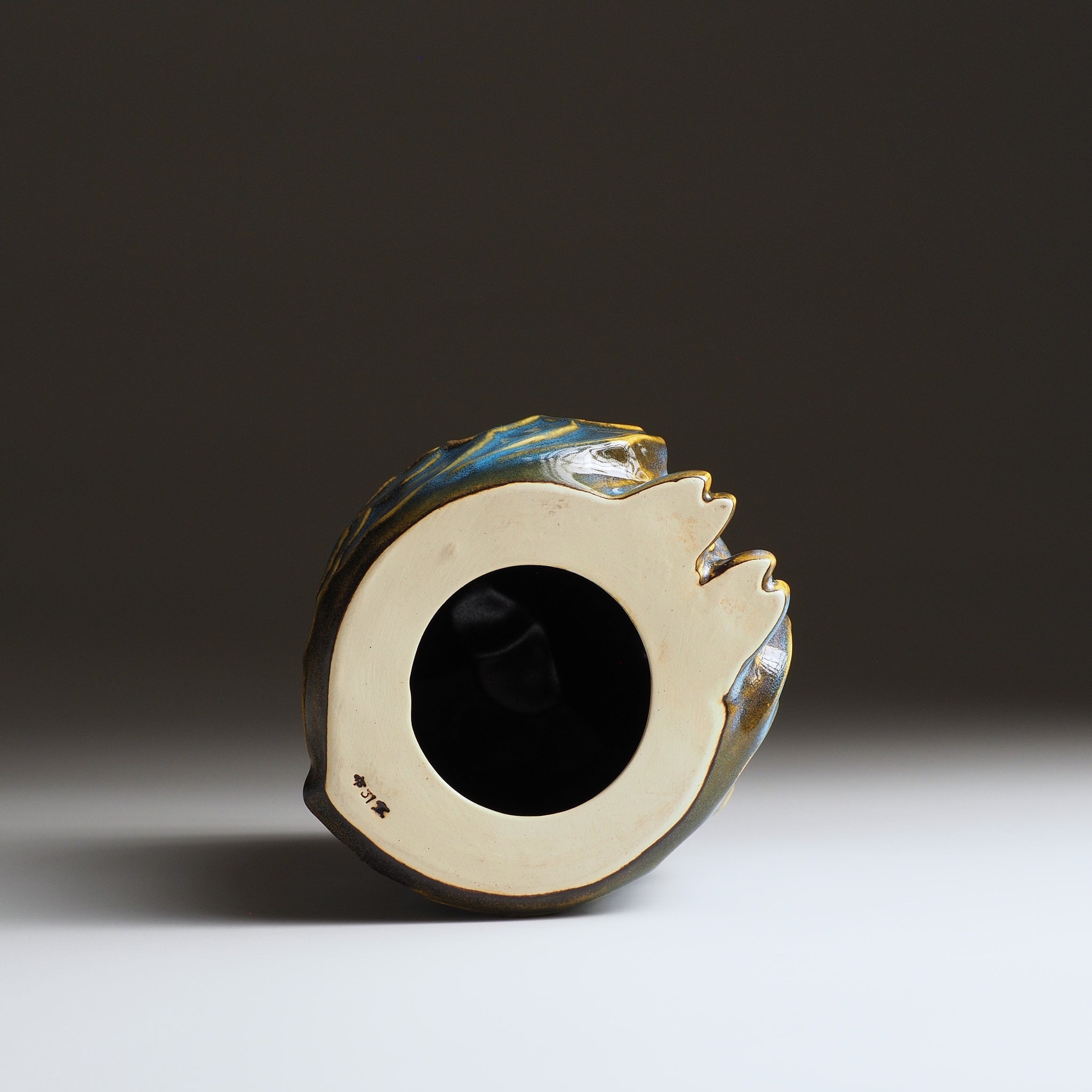 Bottom view of the Fukumori medium ceramic owl figurine by Kazuhiro Kojima, unglazed stoneware base on a faded background.