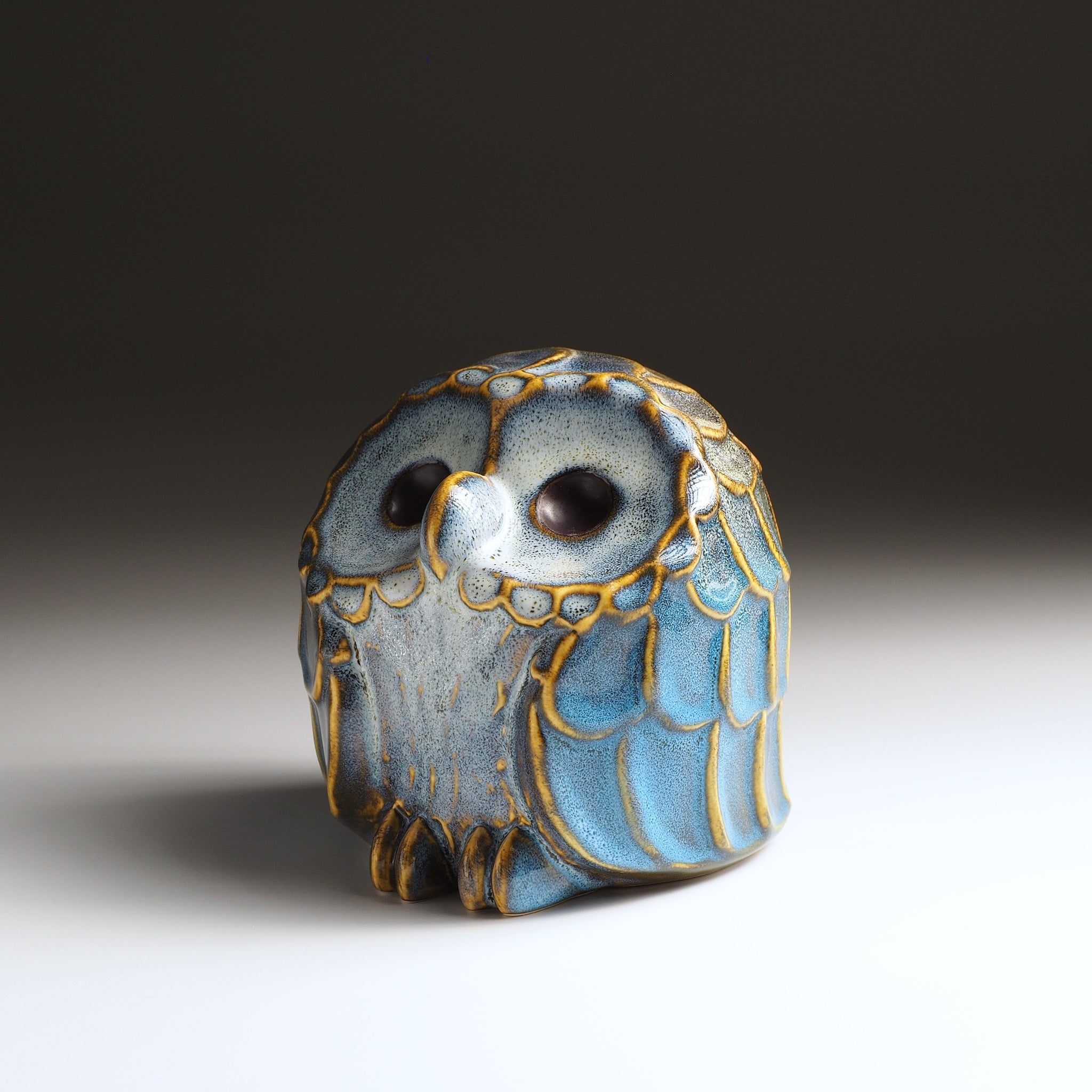 Medium Fukumori owl-shaped ceramic ornament with blue glaze and gold feather details, three-quarter front view