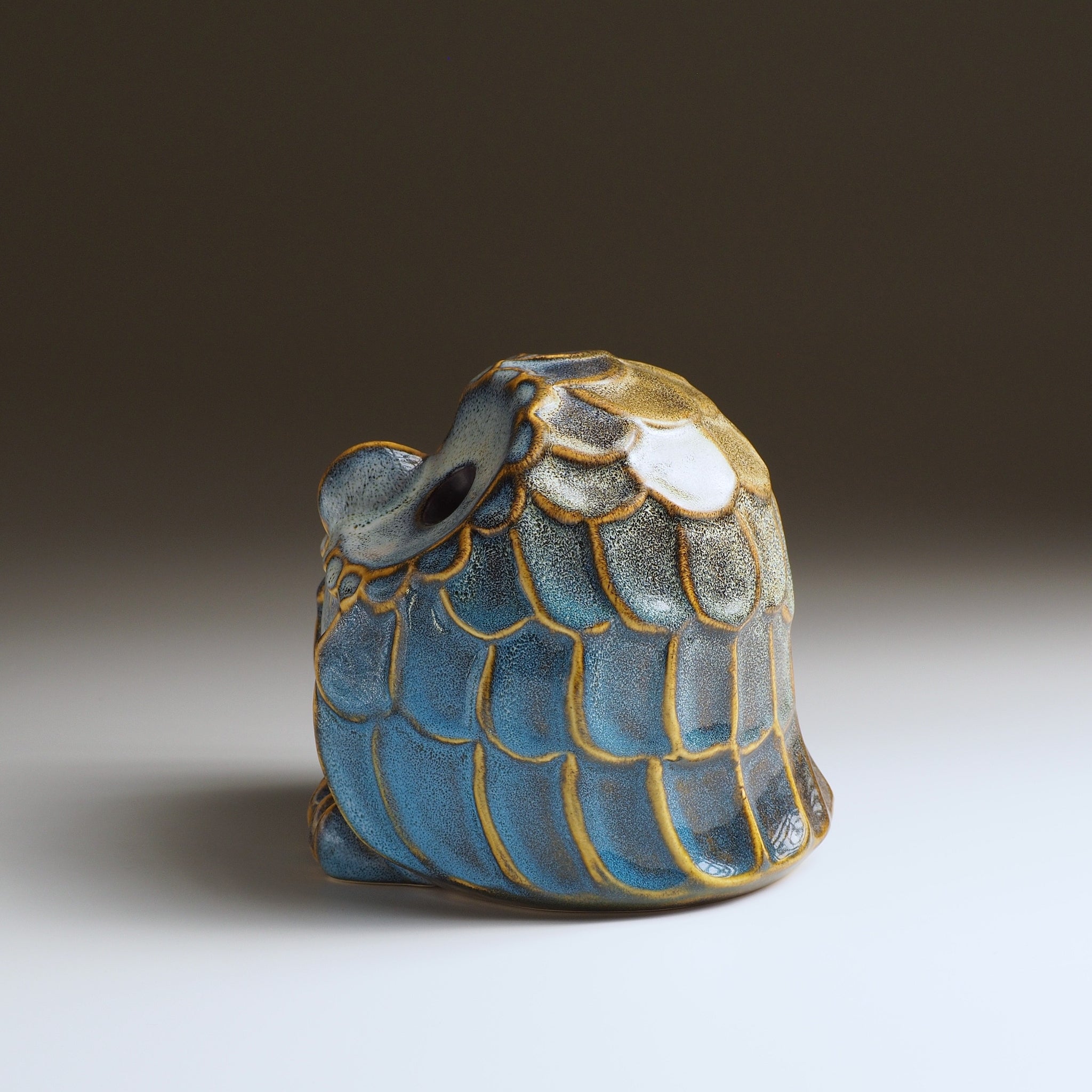 Side view of the medium Fukumori ceramic owl ornament showing layered blue and gold feather decoration