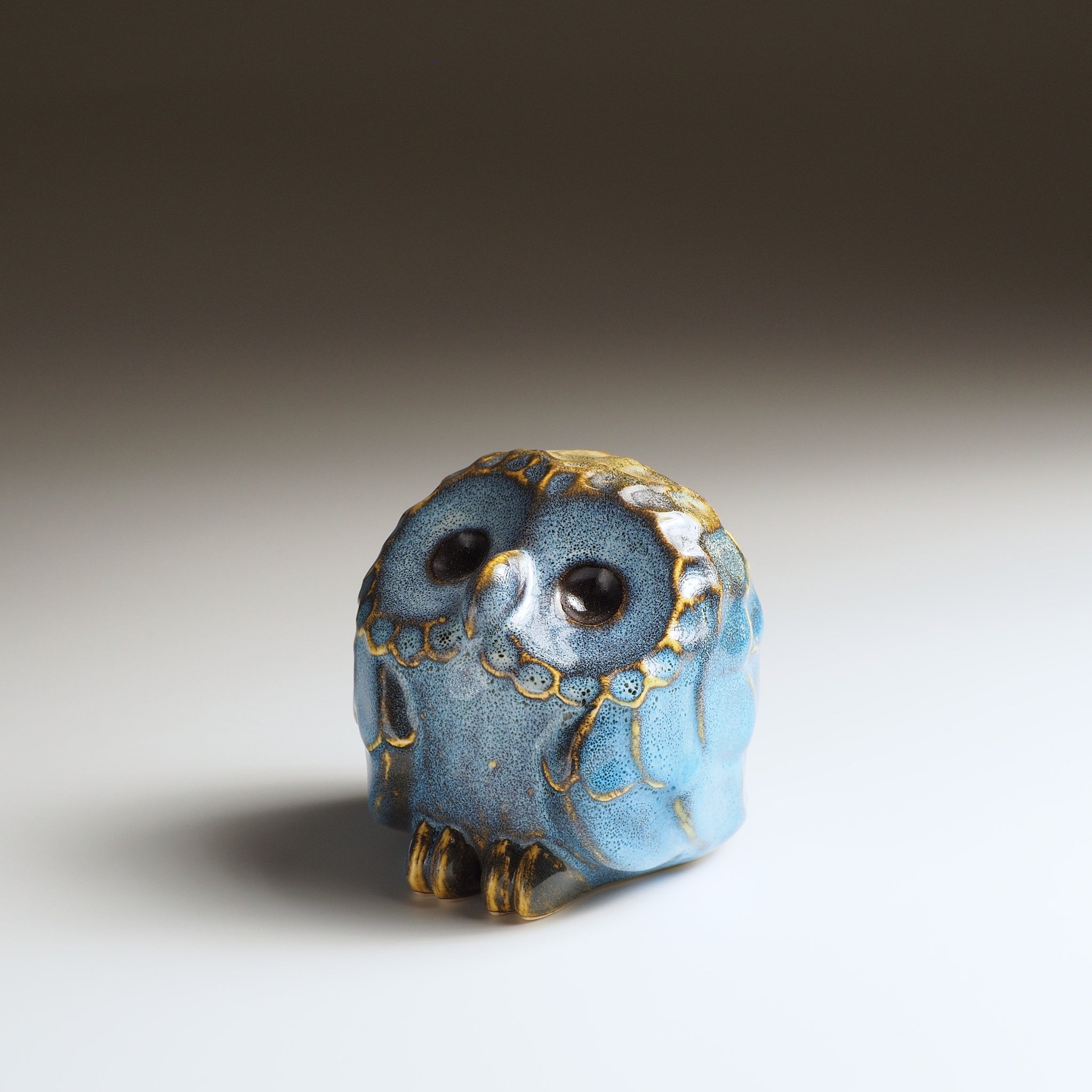 Small Fukumori owl-shaped ceramic ornament with blue glaze and gold accents, three-quarter front view