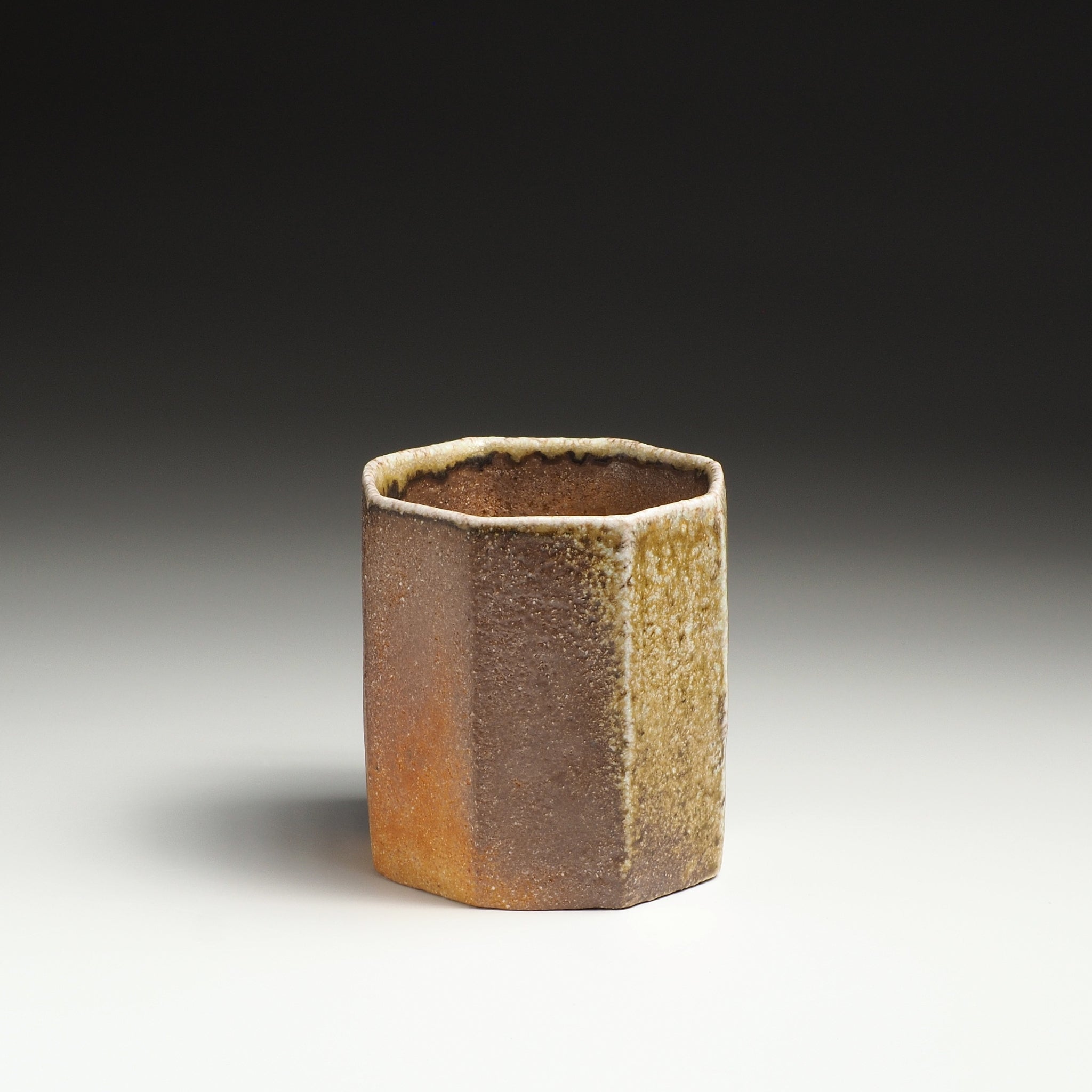 Single Hachiryō handmade Shigaraki cup showing its octagonal form and warm brown and amber firing tones.
