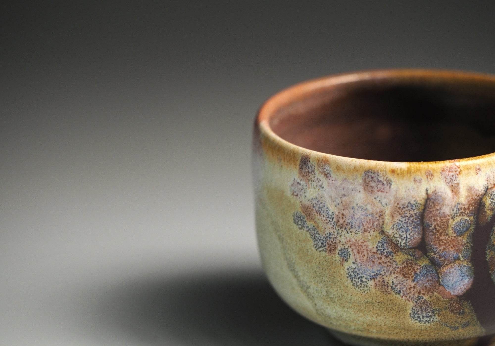 Detail of a Japanese sake cup with sakura decorations on a dark background