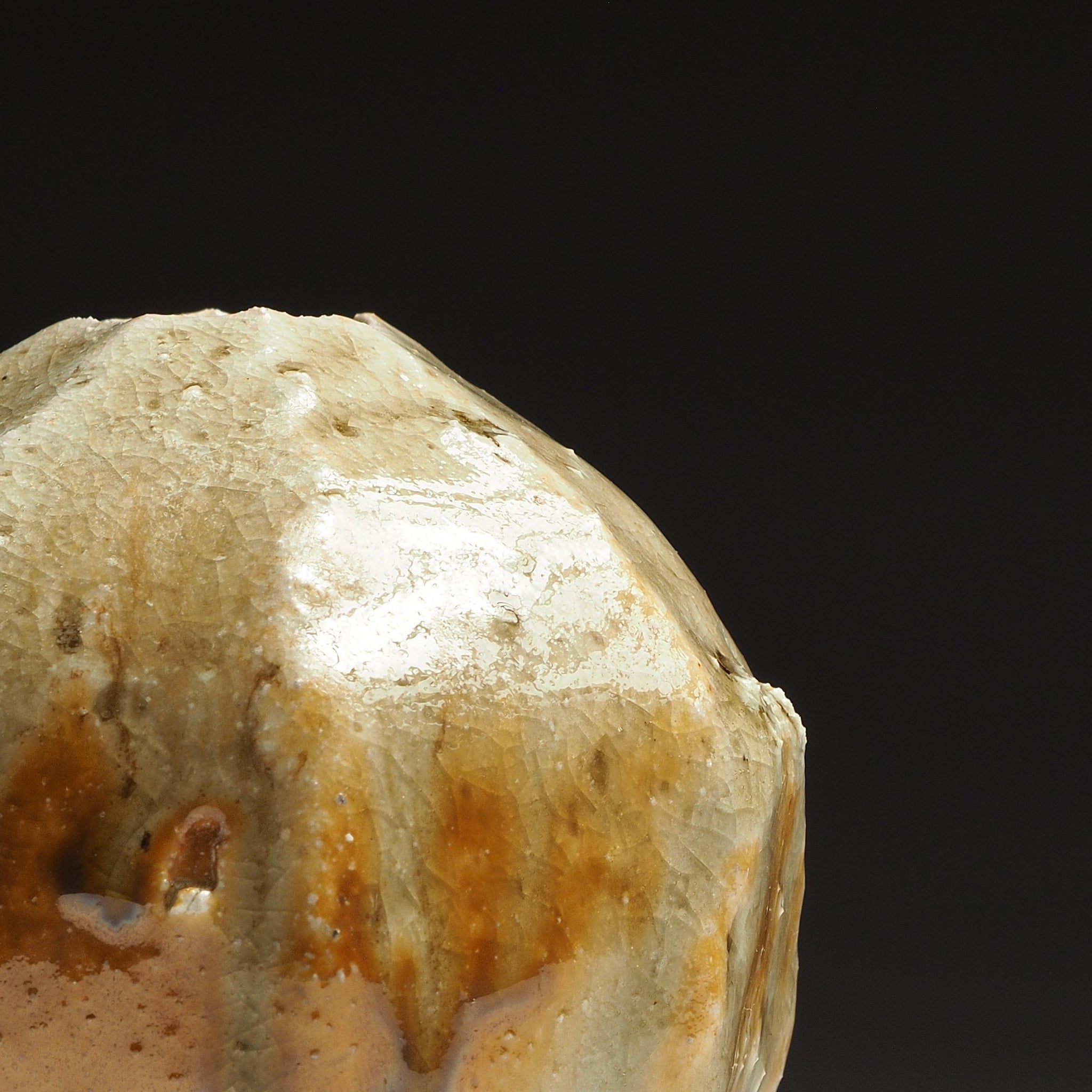 Close-up of the Kokeishi handmade Shigaraki vase showing its faceted surface and flowing beige and amber glaze.