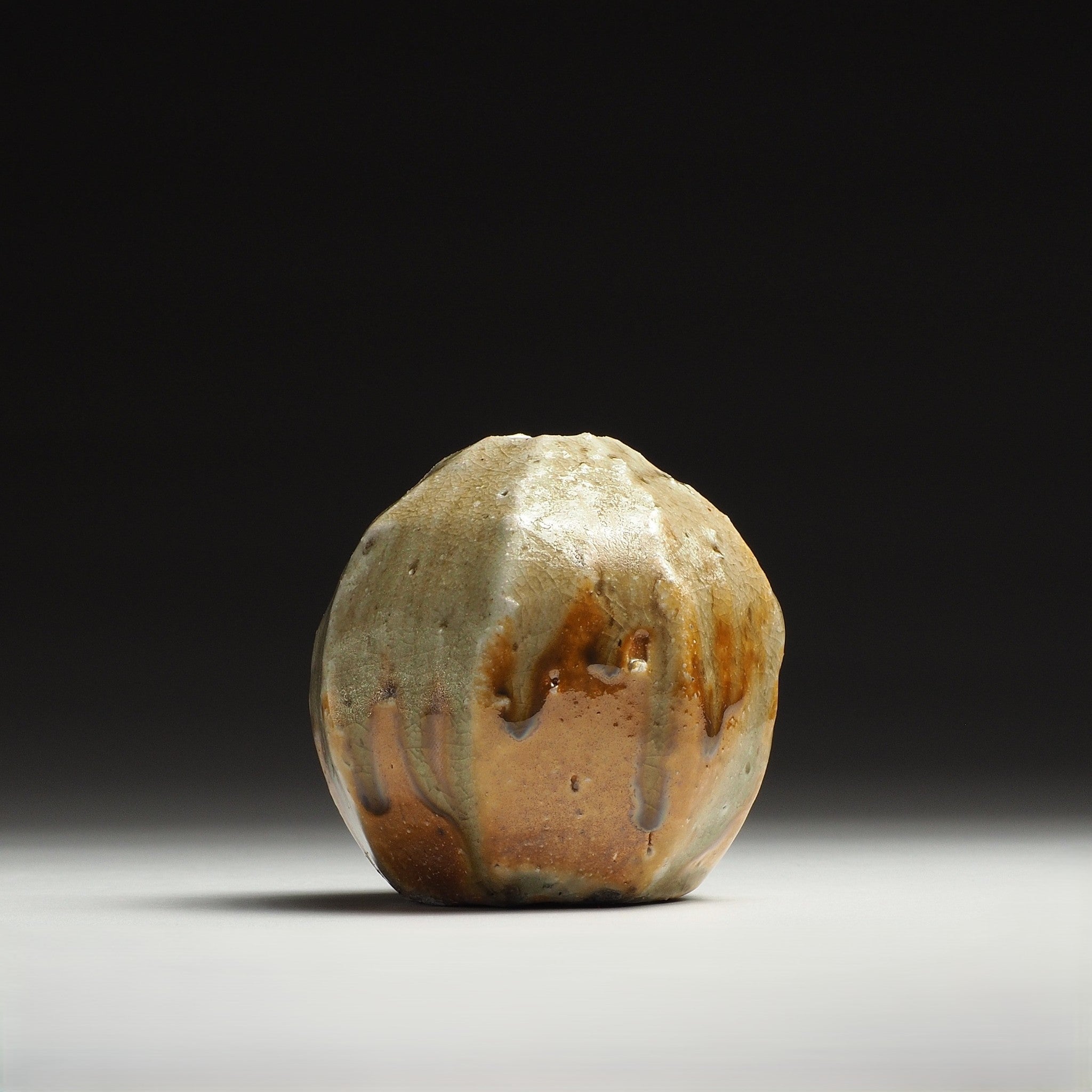 Kokeishi handmade Shigaraki flower vase with a rounded faceted form and mottled beige, amber, and brown surface.