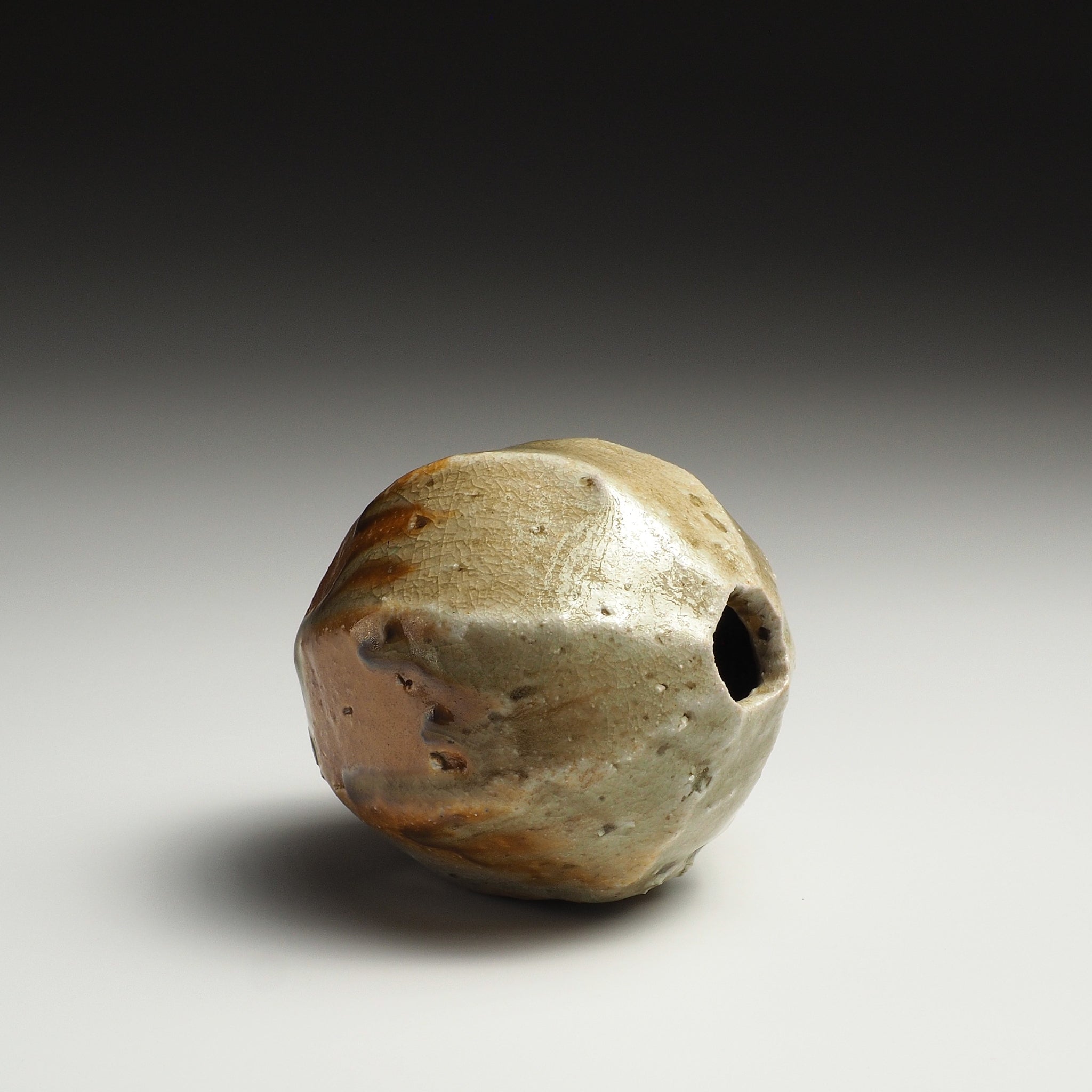 Side view of the Kokeishi handmade Shigaraki flower vase showing the small flower opening and rounded faceted body.