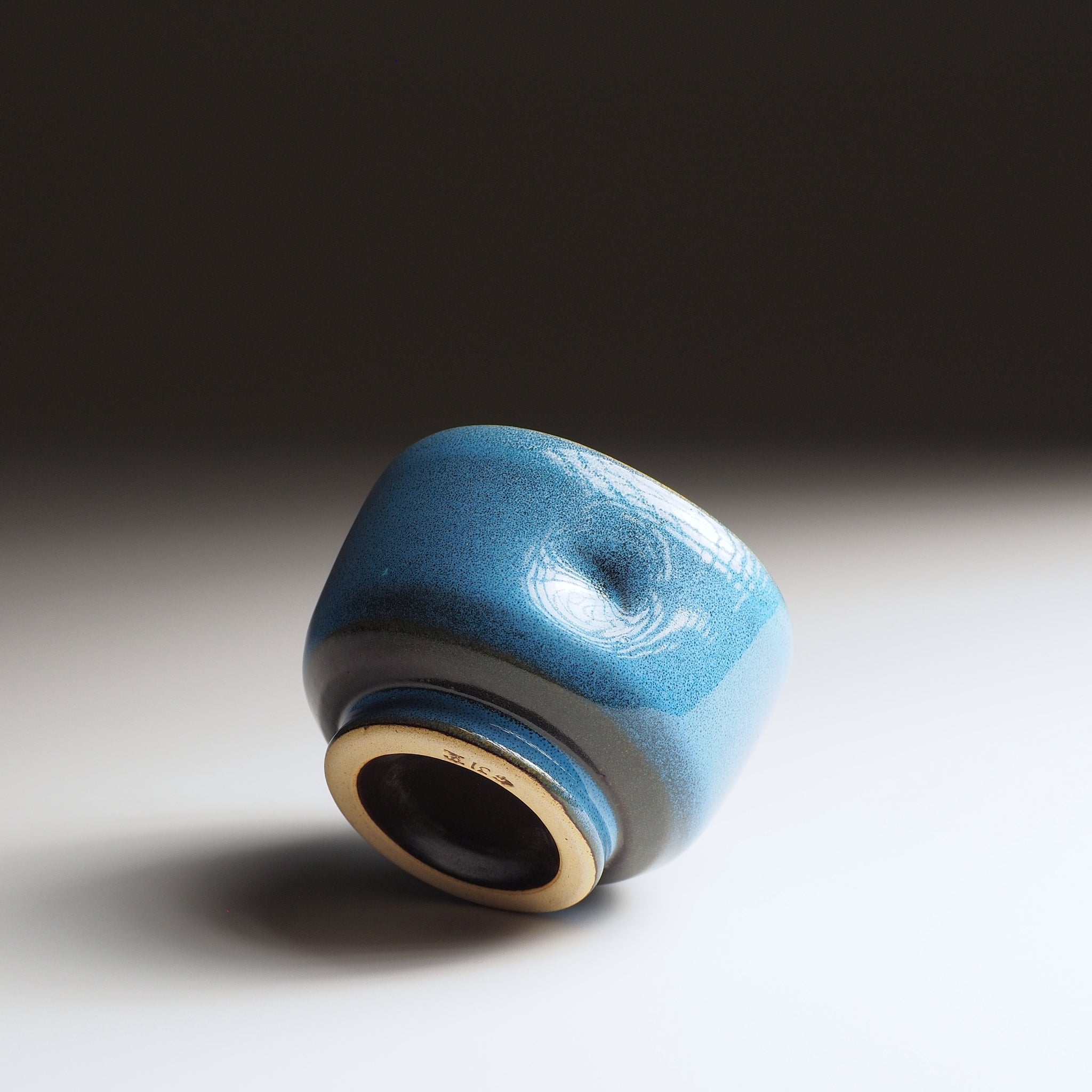 Back view of the Maru Komorebi Yunomi blue teacup, showing the unglazed foot, on a faded background.