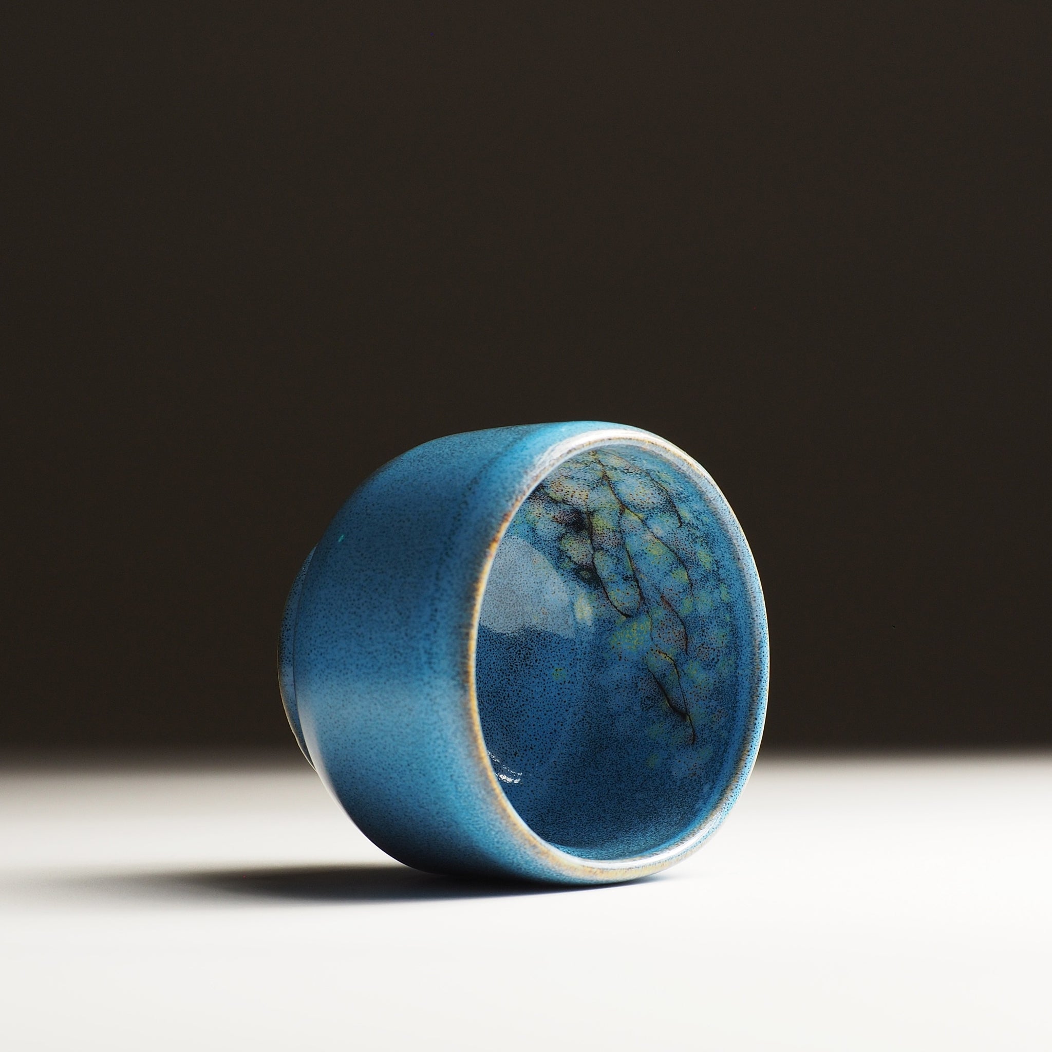 Internal side view of the Maru Komorebi Yunomi blue teacup on a faded background.